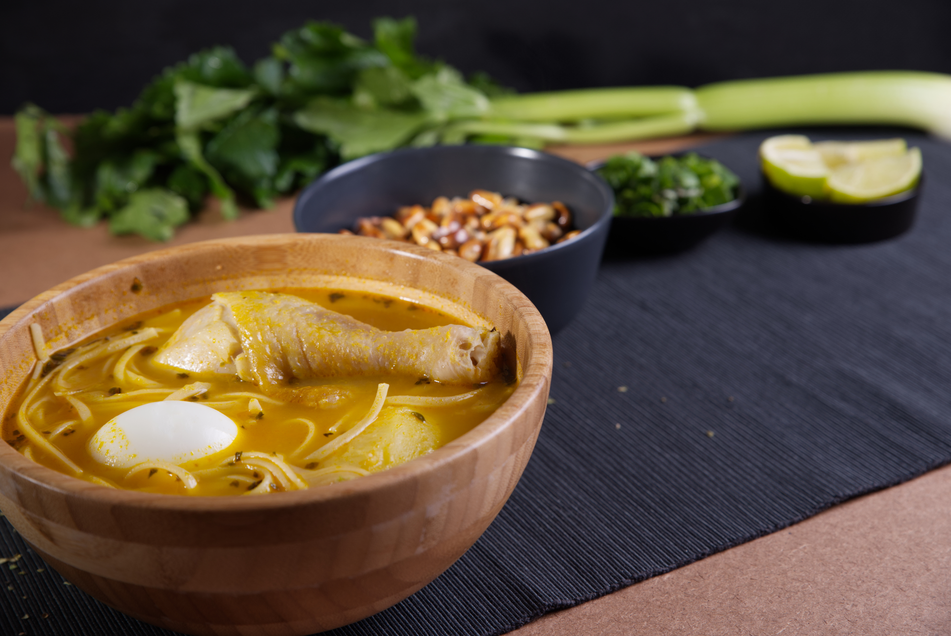 Overhead flat-lay of all ingredients for Aromatic Burmese Fish Noodle Soup with Turmeric and Lime laid out on a kitchen surface.