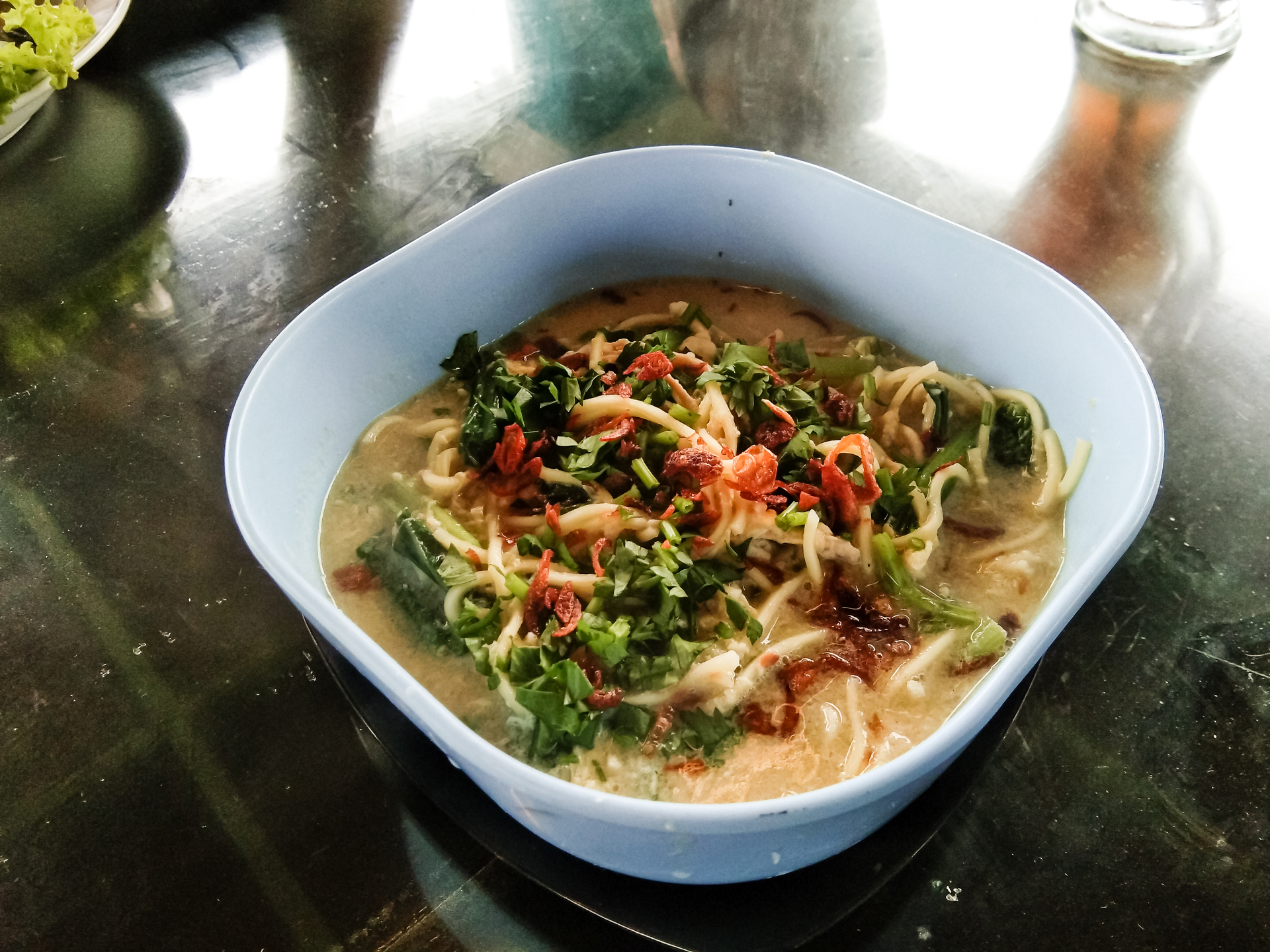 Overhead flat-lay of all ingredients for Aromatic Cambodian Noodle Soup with Lime and Tamarind laid out on a kitchen surface.