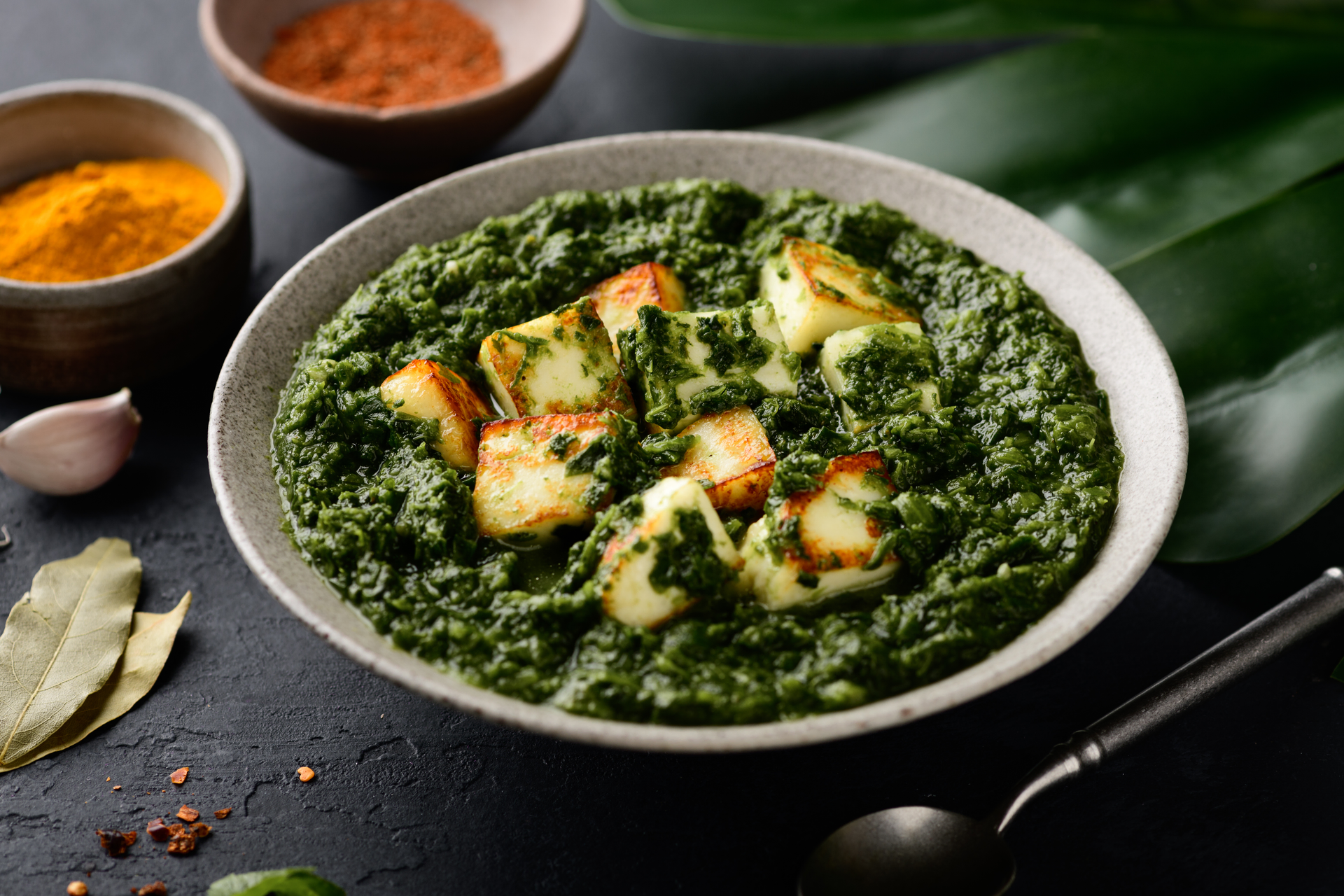 Overhead flat-lay of all ingredients for Aromatic Indian Palak Paneer with Fenugreek laid out on a kitchen surface.