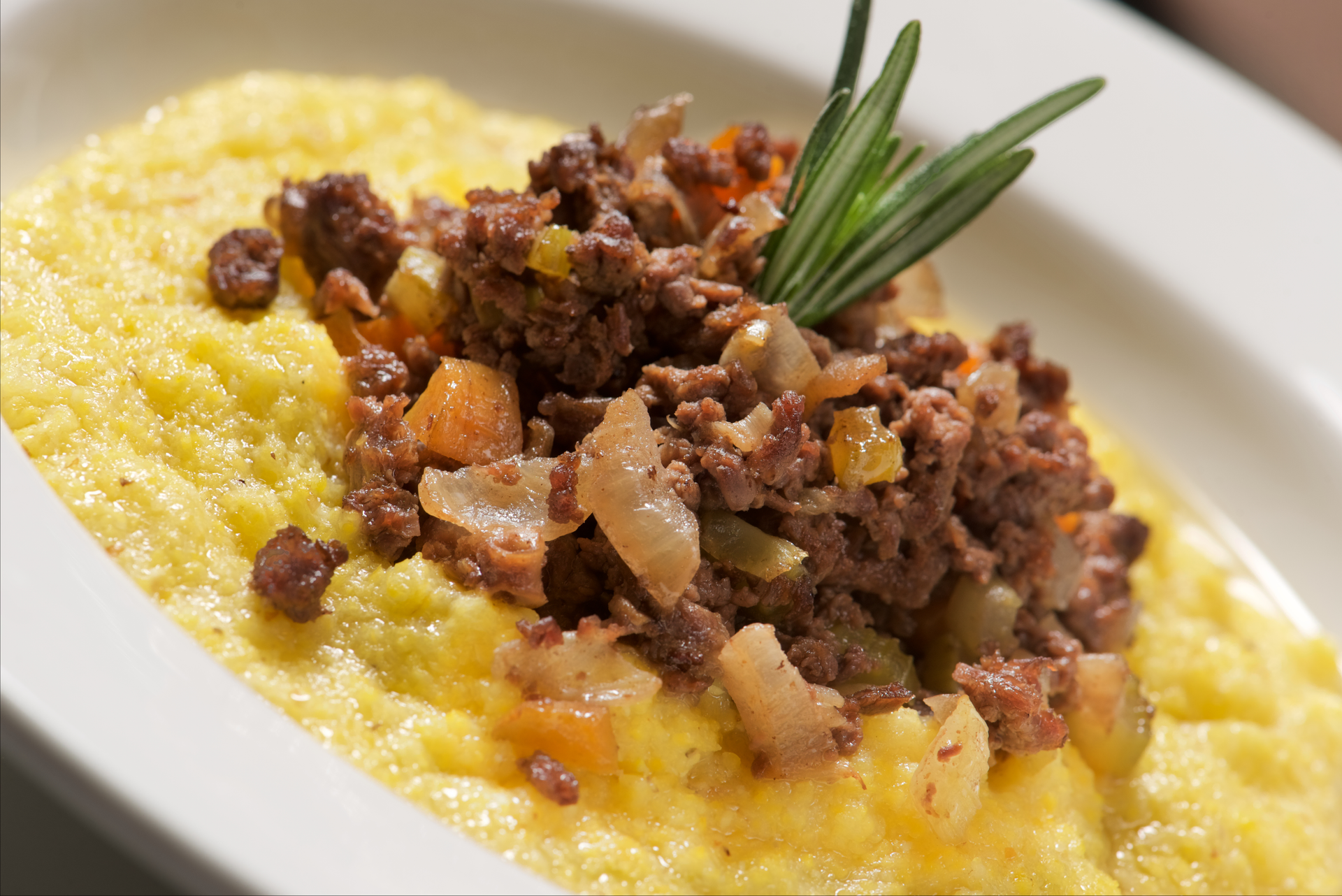 Overhead flat-lay of all ingredients for Aromatic Italian Lamb Ragu with Rosemary Polenta laid out on a kitchen surface.