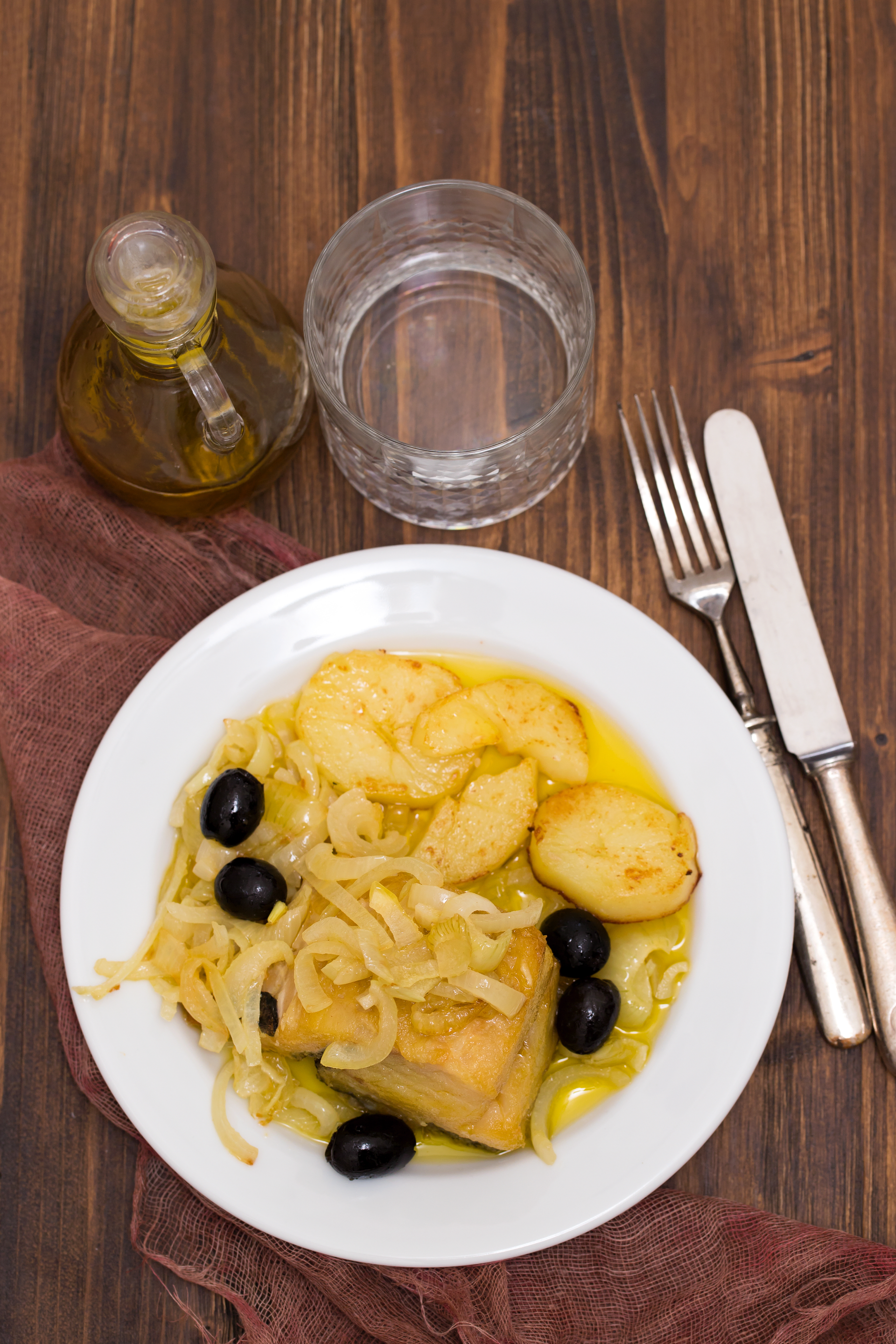 Overhead flat-lay of all ingredients for Aromatic Portuguese Bacalhau à Brás with Olive Garnish laid out on a kitchen surface.