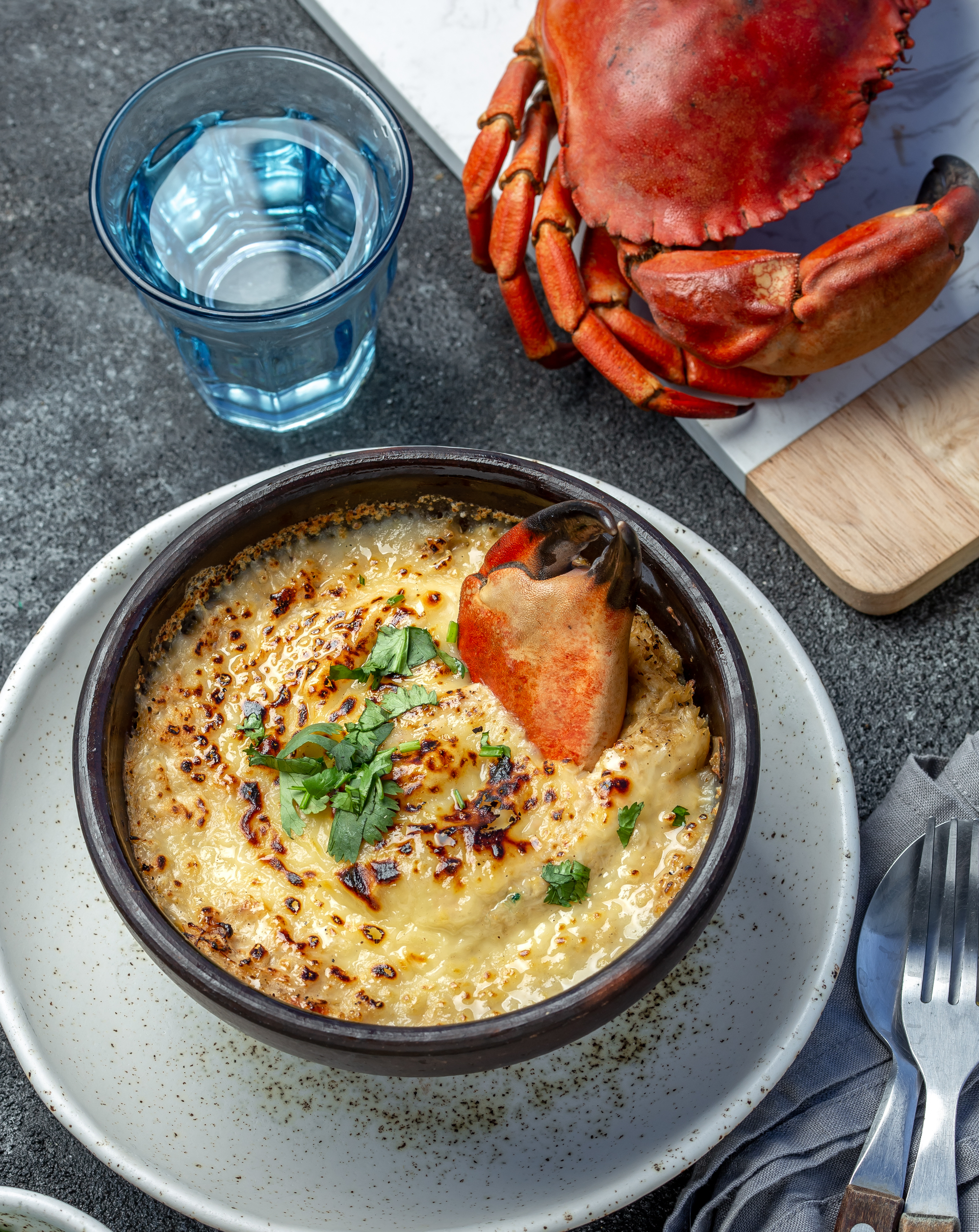 Overhead flat-lay of all ingredients for Basque Txangurro a la Donostiarra with Crab and Brandy laid out on a kitchen surface.