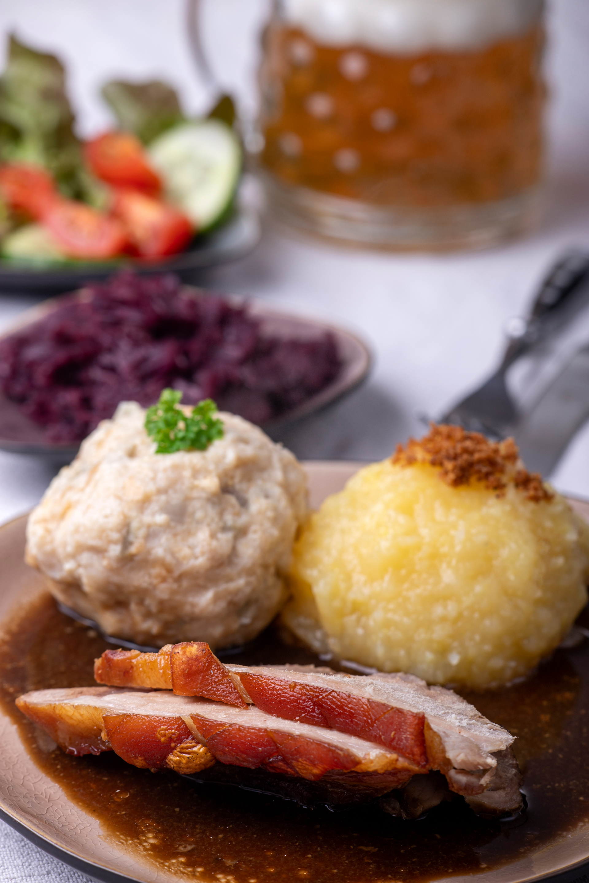 Overhead flat-lay of all ingredients for Bavarian Schweinshaxe with Sauerkraut and Potato Dumplings laid out on a kitchen surface.