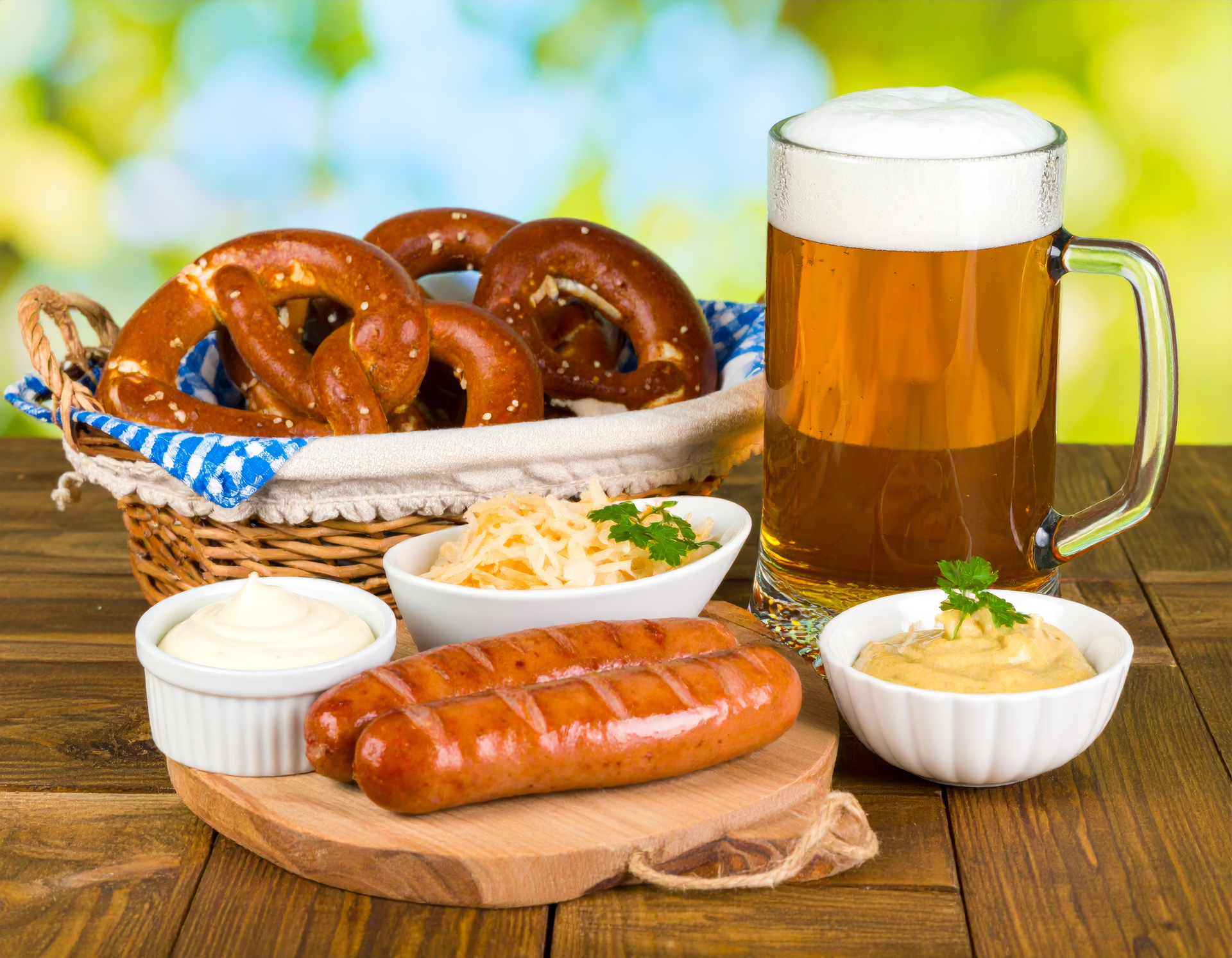 Overhead flat-lay of all ingredients for Bavarian Weisswurst with Sweet Mustard and Pretzel laid out on a kitchen surface.