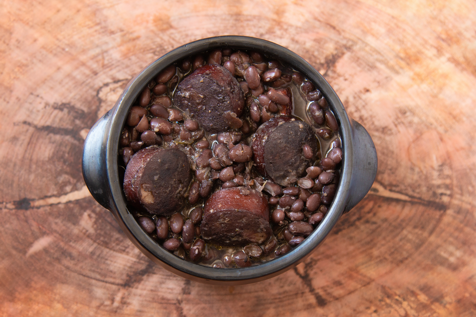 Overhead flat-lay of all ingredients for Brazilian Feijoada with Pork Hocks and Black Beans laid out on a kitchen surface.