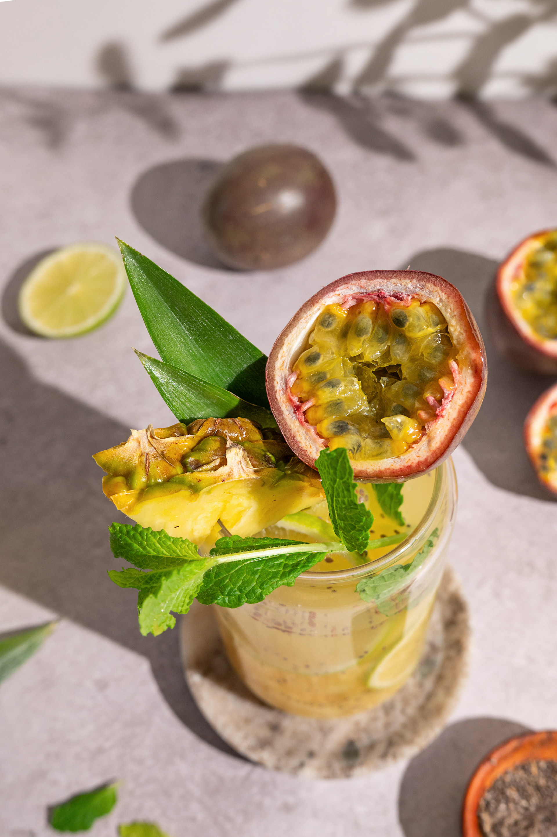 Overhead flat-lay of all ingredients for Brazilian Lime Caipirinha with Passionfruit Twist laid out on a kitchen surface.