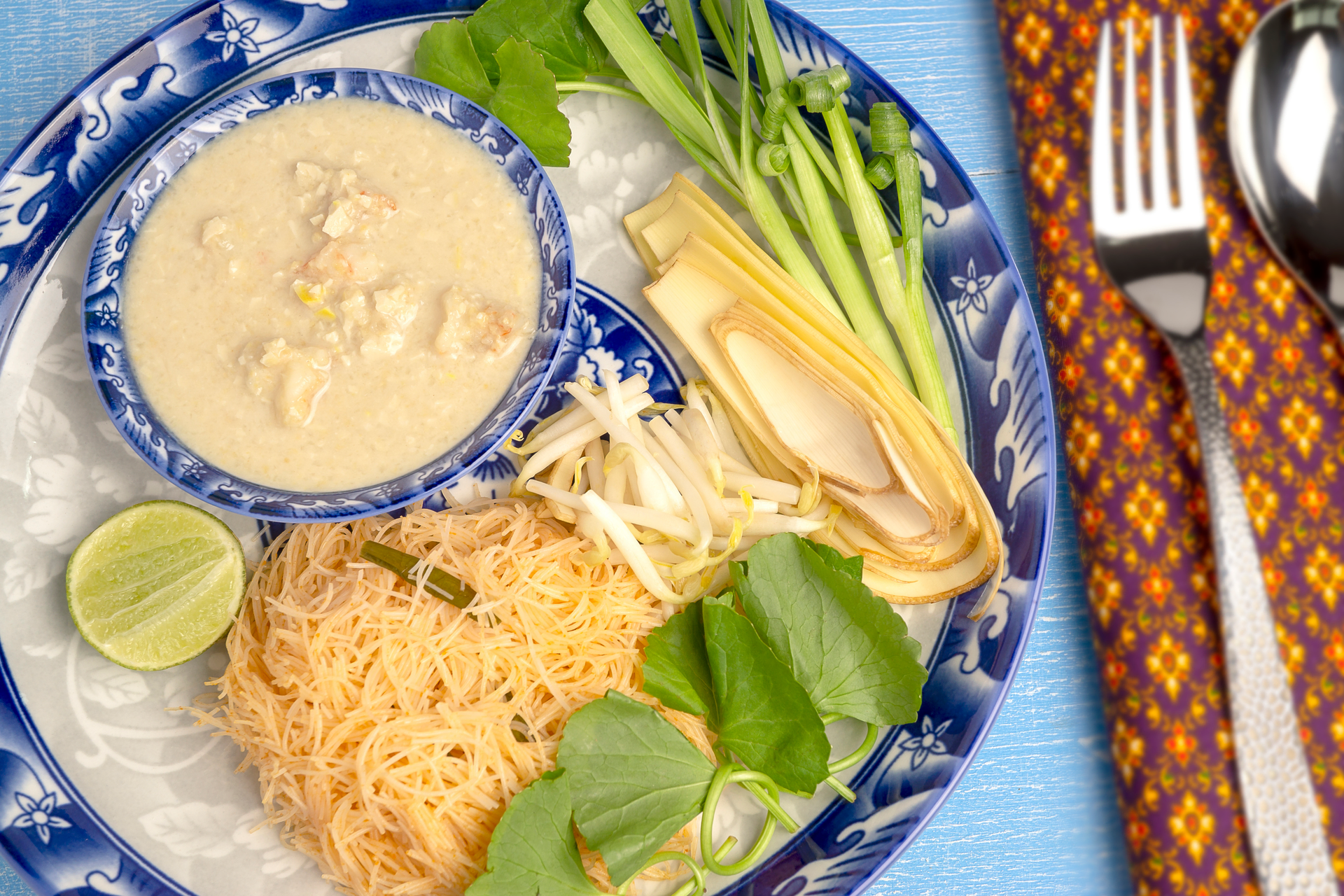 Overhead flat-lay of all ingredients for Burmese Coconut Noodle Soup with Lemongrass Chicken laid out on a kitchen surface.