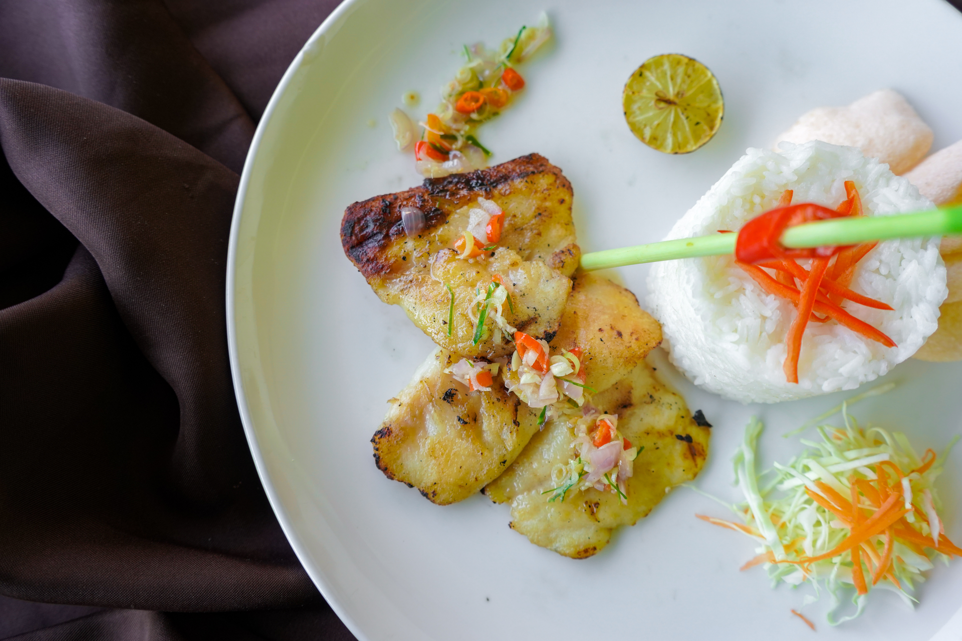 Overhead flat-lay of all ingredients for Burmese Grilled Lemongrass Chicken with Coconut Rice laid out on a kitchen surface.