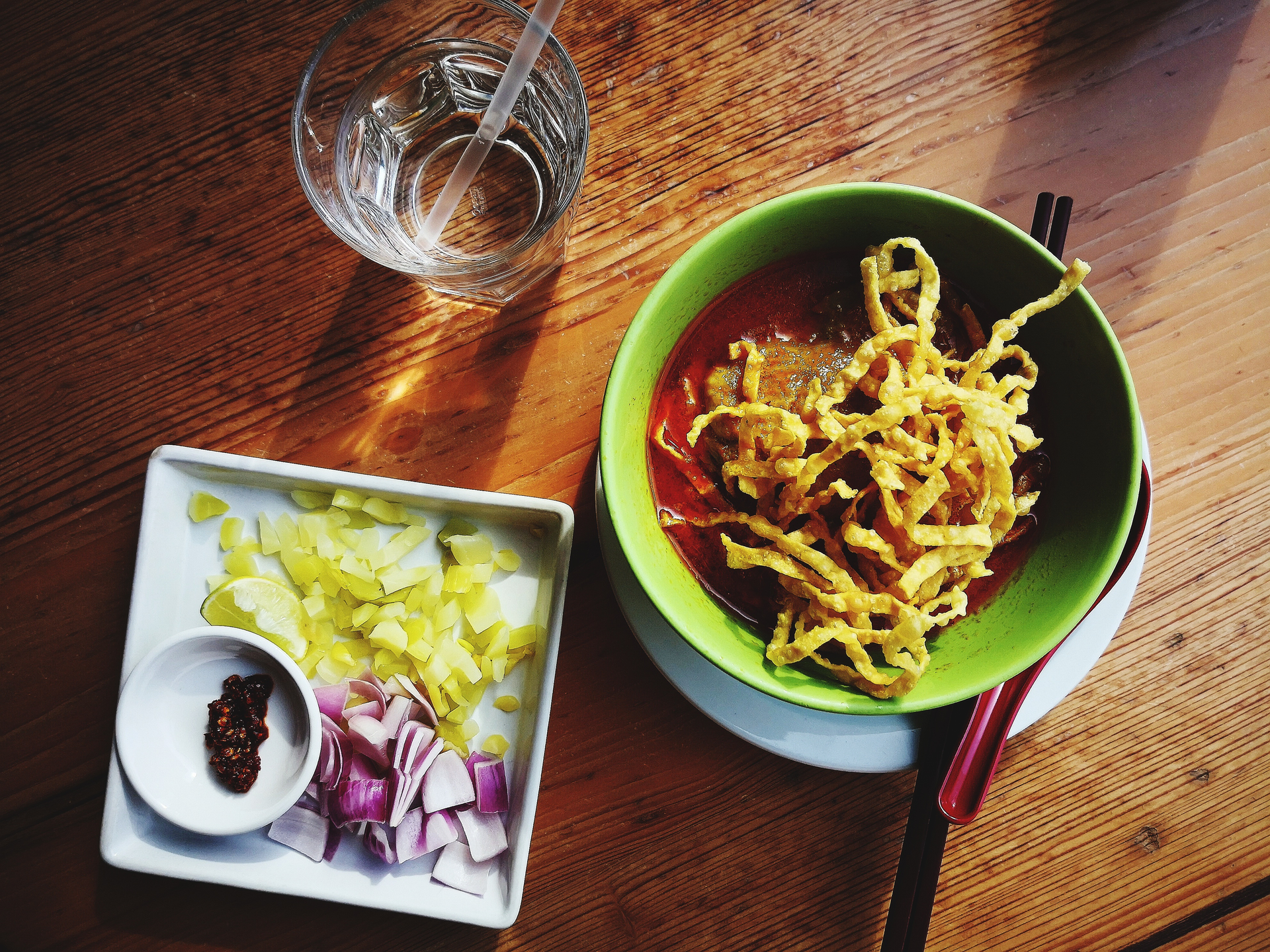 Overhead flat-lay of all ingredients for Burmese Shan Noodles with Pork and Pickled Mustard Greens laid out on a kitchen surface.