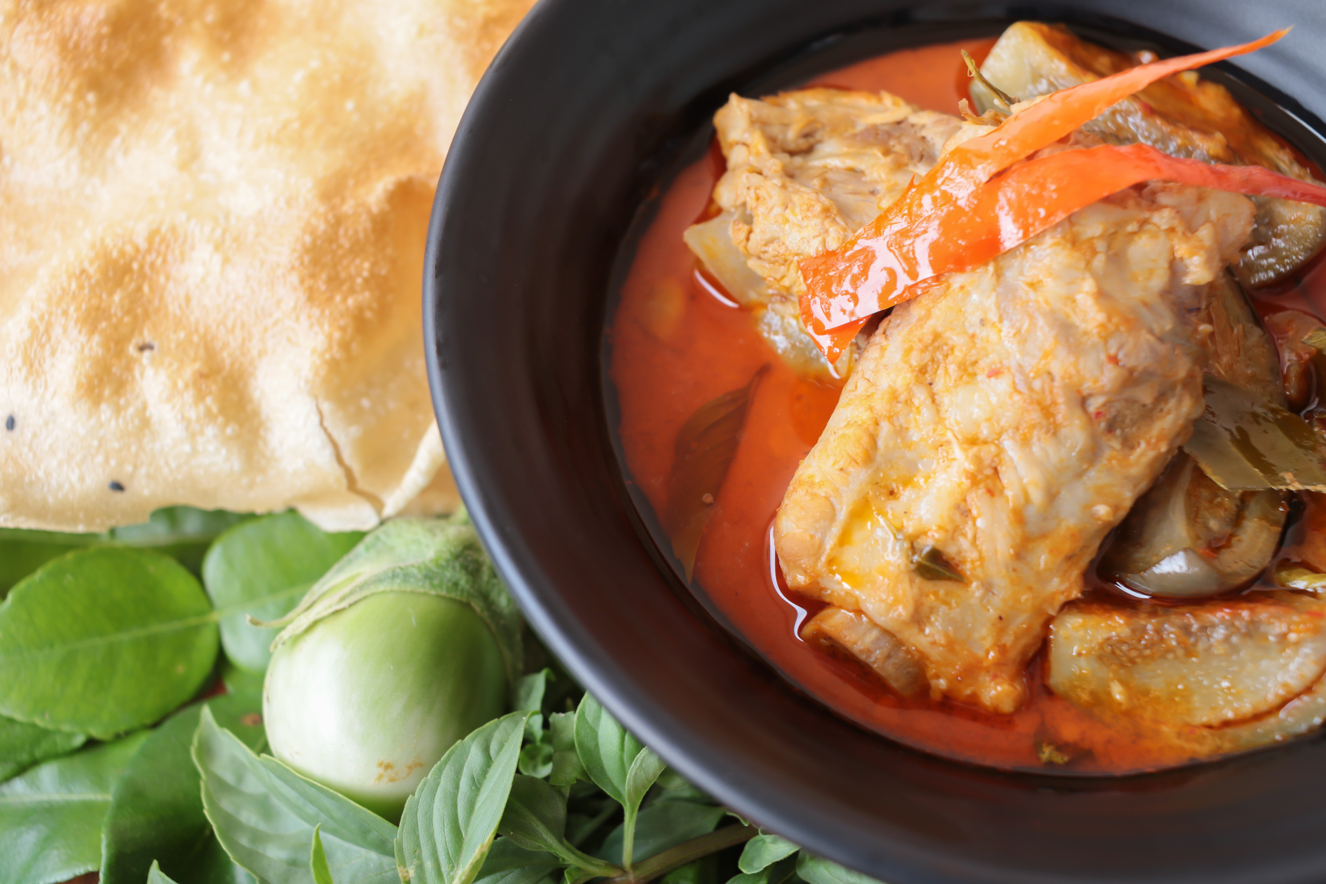 Overhead flat-lay of all ingredients for Burmese Tomato Fish Curry with Tamarind Paste laid out on a kitchen surface.
