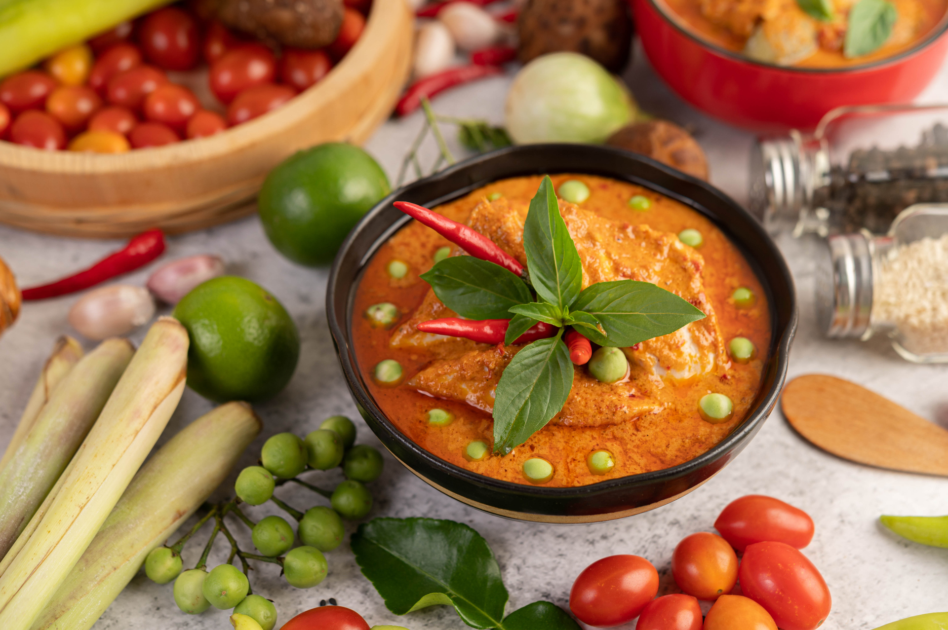 Overhead flat-lay of all ingredients for Burmese Tomato Tofu Curry with Lemongrass laid out on a kitchen surface.