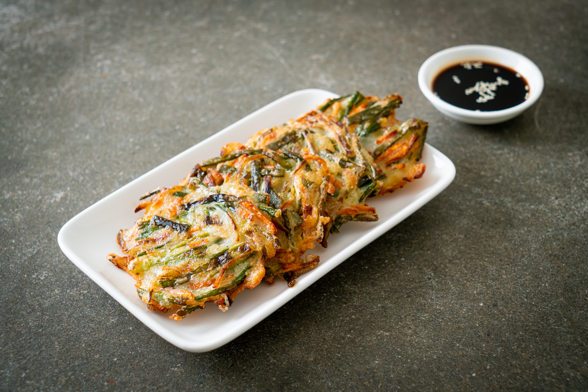 Overhead flat-lay of all ingredients for Caramelized Korean Jeon with Green Onion and Garlic Chives laid out on a kitchen surface.