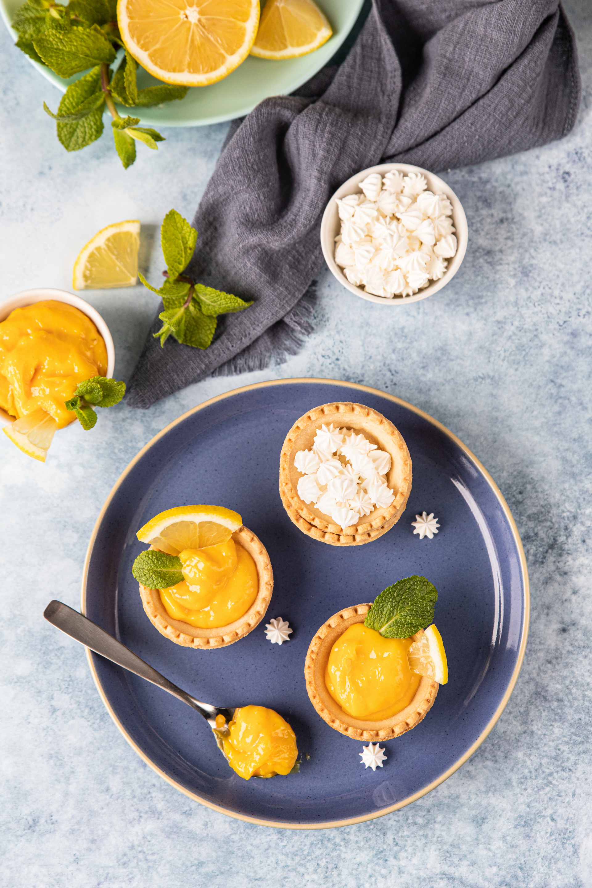 Overhead flat-lay of all ingredients for Citrusy Greek Avgolemono Mini Tarts with Lemon Zest laid out on a kitchen surface.