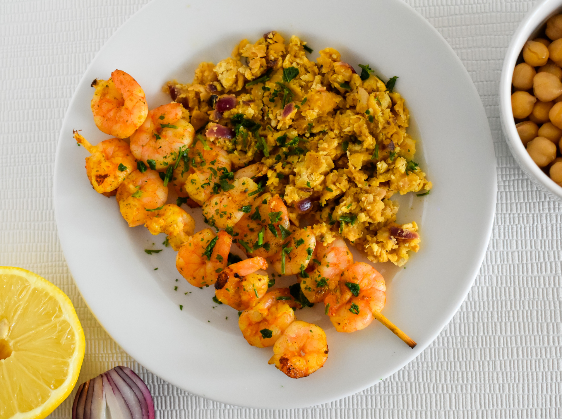 Overhead flat-lay of all ingredients for Citrusy Moroccan Chermoula Prawns with Couscous laid out on a kitchen surface.