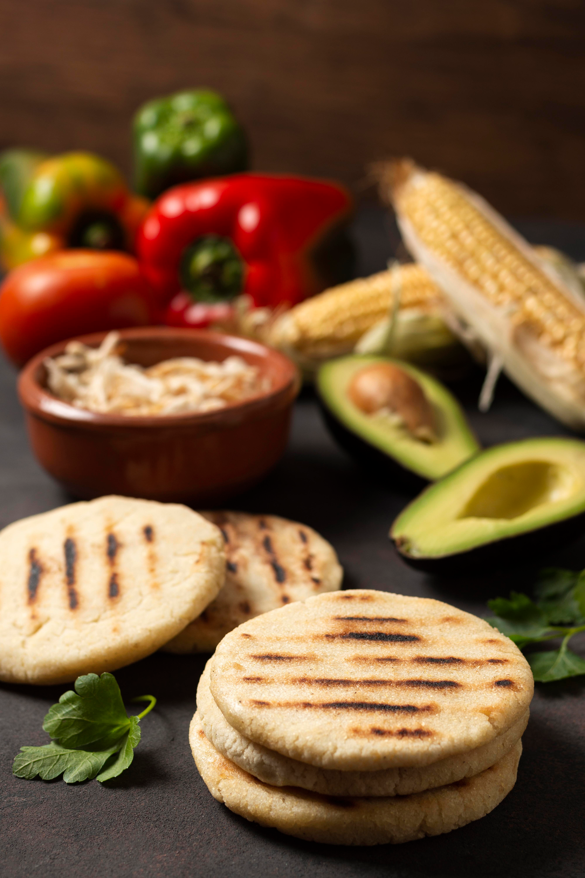 Overhead flat-lay of all ingredients for Colombian Arepas with Spicy Guacamole laid out on a kitchen surface.