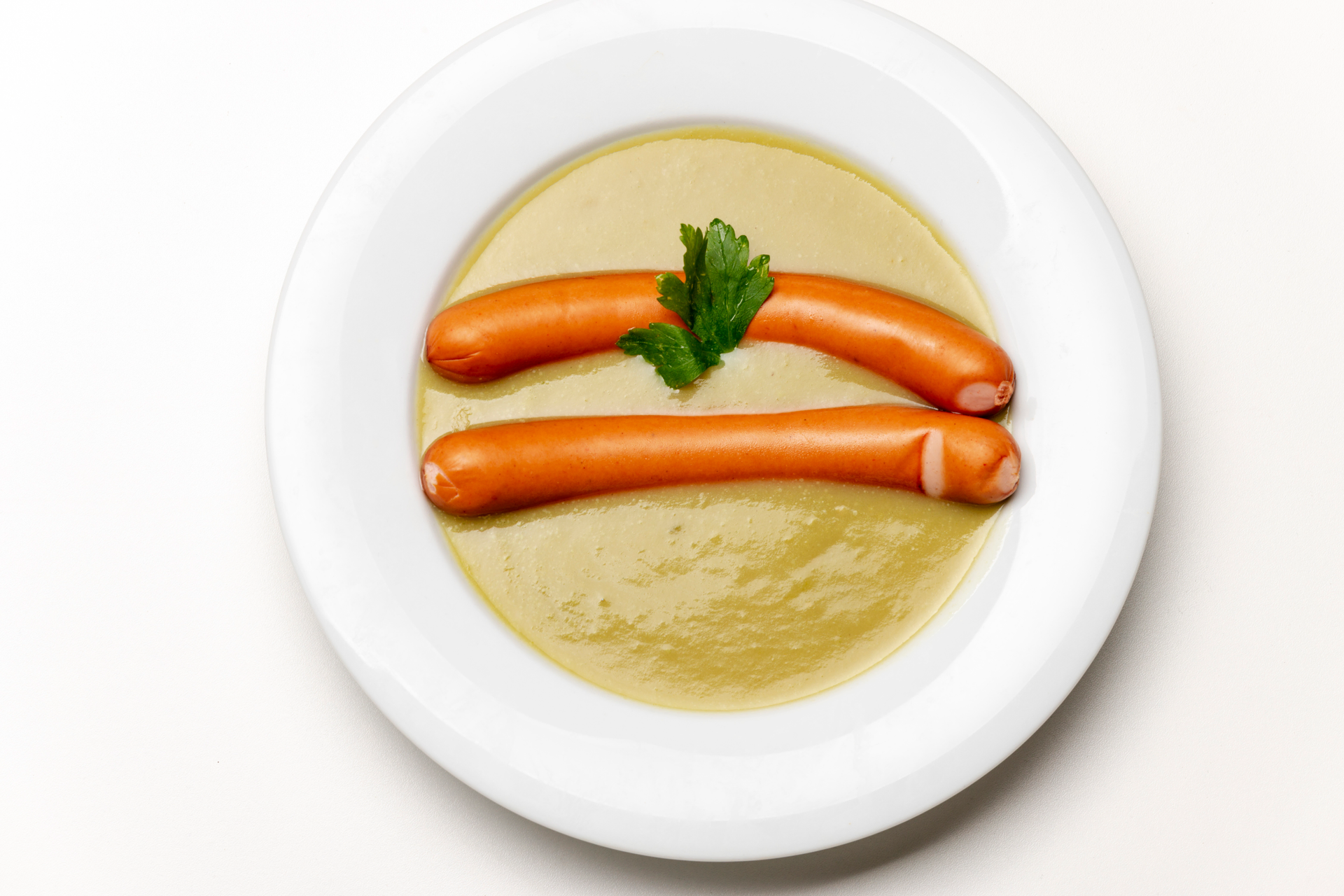 Overhead flat-lay of all ingredients for Creamy Dutch Erwtensoep with Smoked Sausage laid out on a kitchen surface.