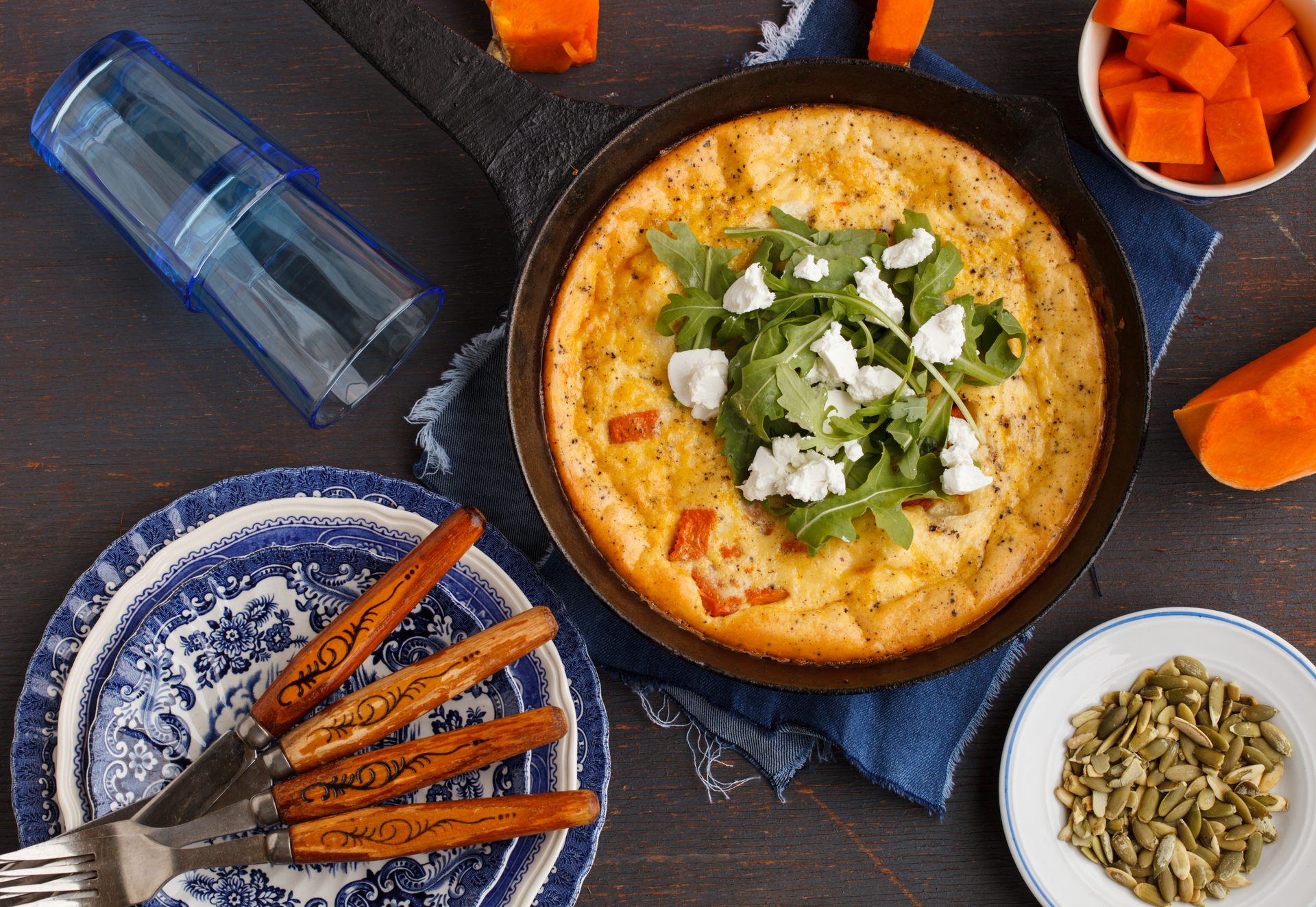 Overhead flat-lay of all ingredients for Creamy Ethiopian Teff Frittata with Berbere-Spiced Tomatoes laid out on a kitchen surface.