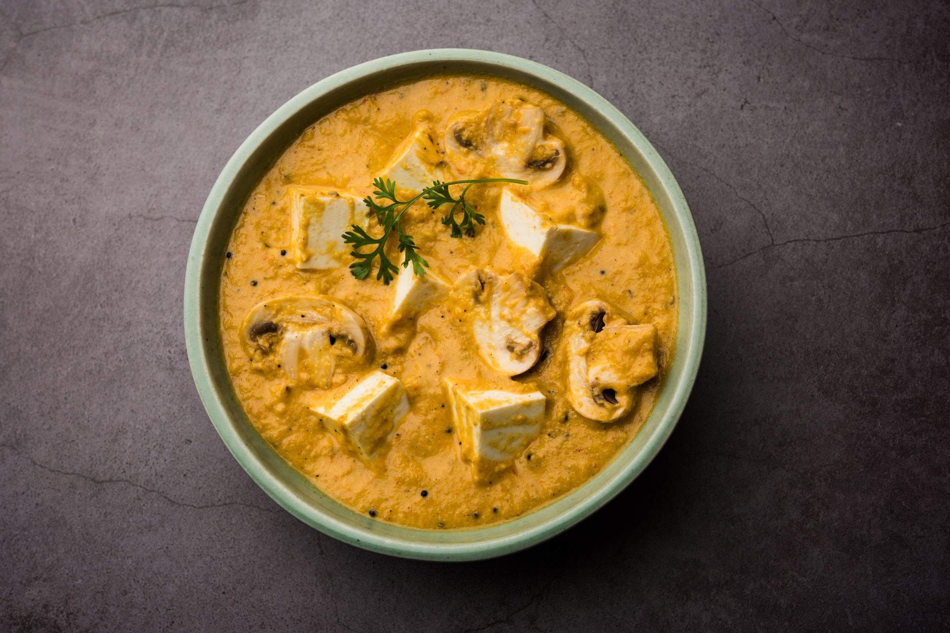 Overhead flat-lay of all ingredients for Creamy Indian Paneer Butter Masala with Cashew Gravy laid out on a kitchen surface.