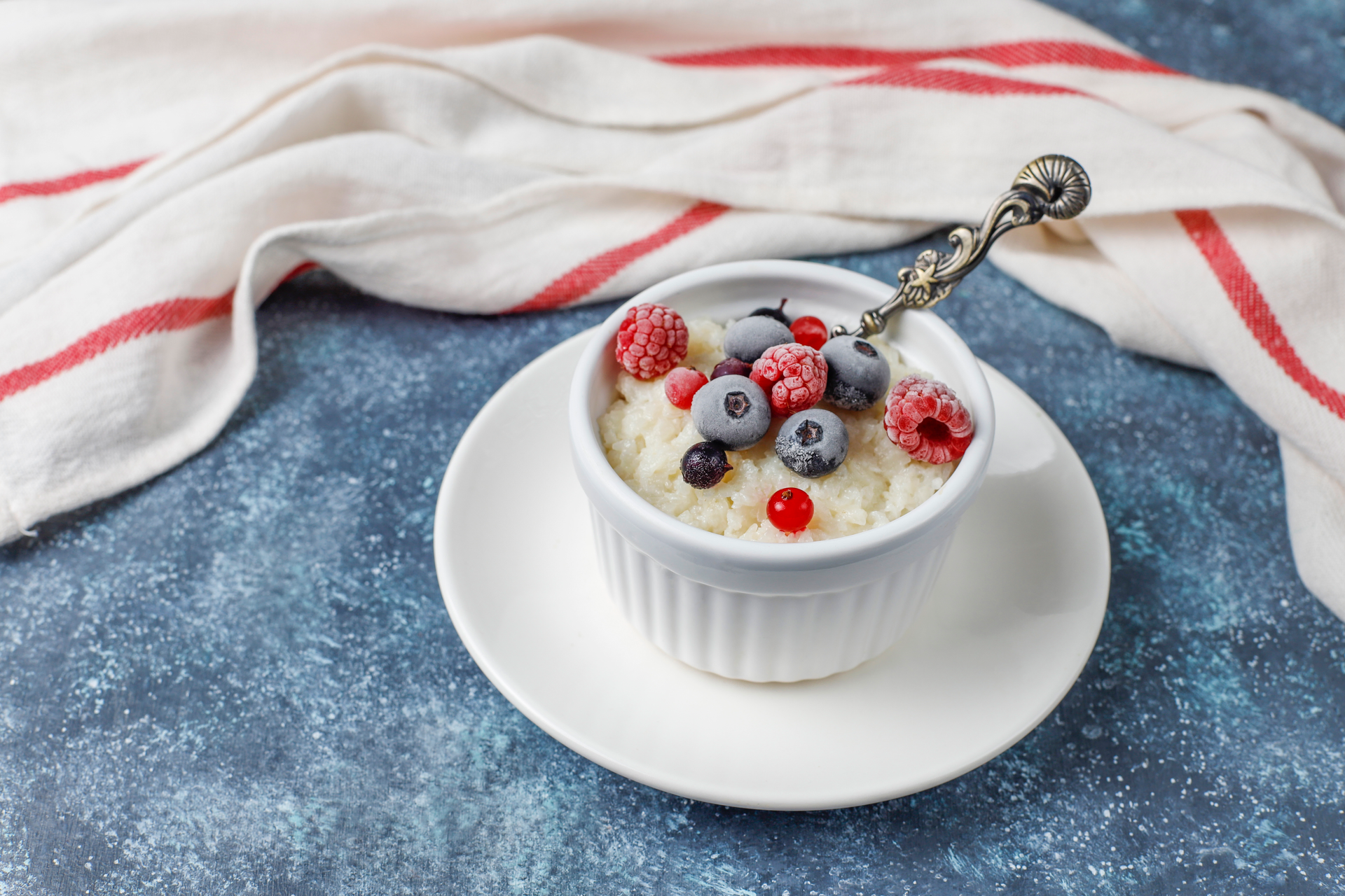 Overhead flat-lay of all ingredients for Creamy Madagascar Vanilla Bean Rice Pudding with Fresh Berries laid out on a kitchen surface.