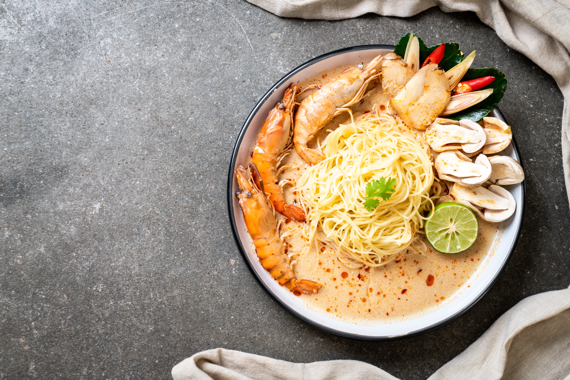 Overhead flat-lay of all ingredients for Creamy Singaporean Laksa with Shrimp and Coconut Milk laid out on a kitchen surface.
