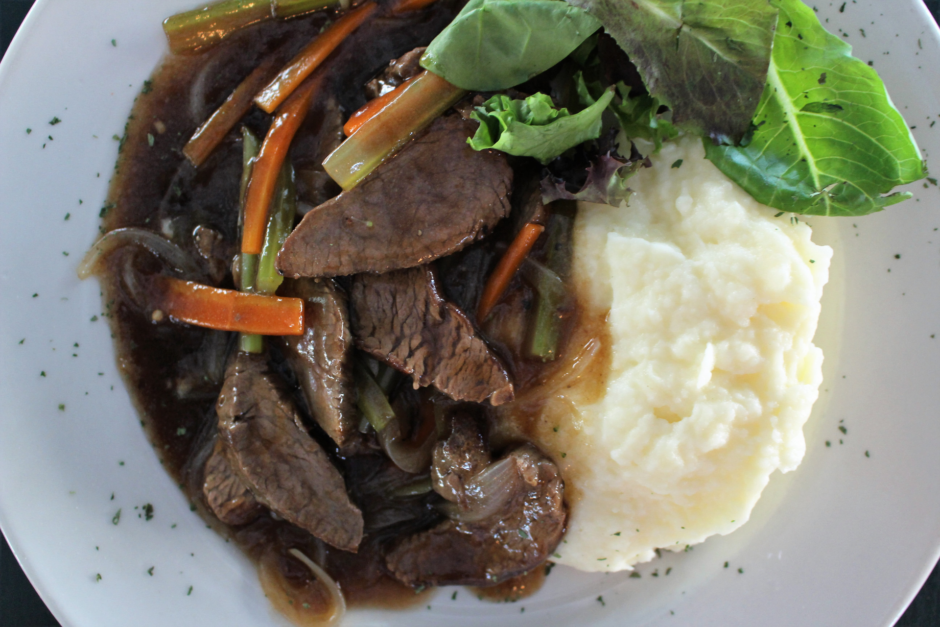 Overhead flat-lay of all ingredients for Creamy Venezuelan Asado Negro laid out on a kitchen surface.