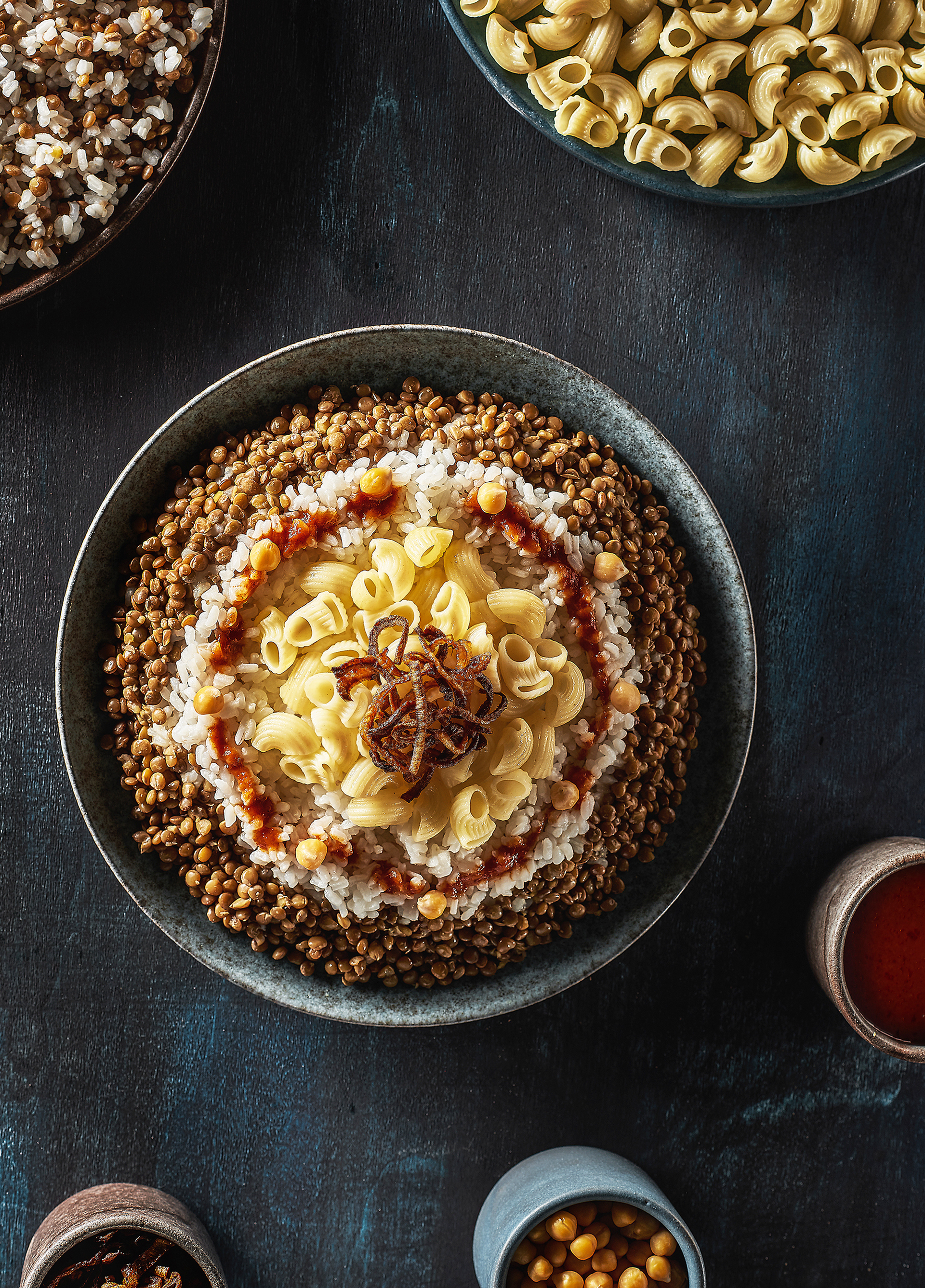 Overhead flat-lay of all ingredients for Egyptian Koshari with Lentils and Crispy Onions laid out on a kitchen surface.