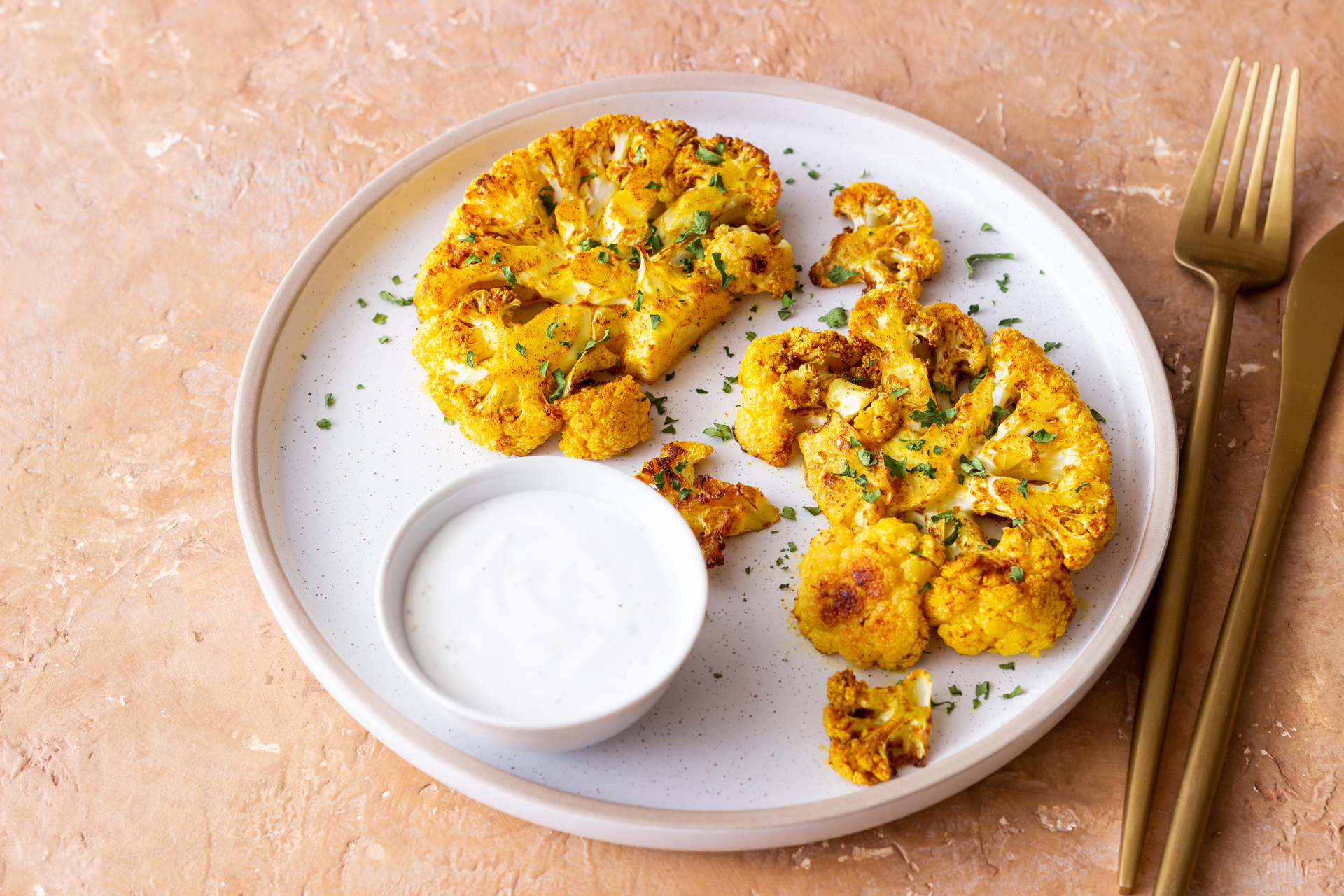 Overhead flat-lay of all ingredients for Exotic Moroccan Spiced Cauliflower Steaks with Honey-Tahini Drizzle laid out on a kitchen surface.