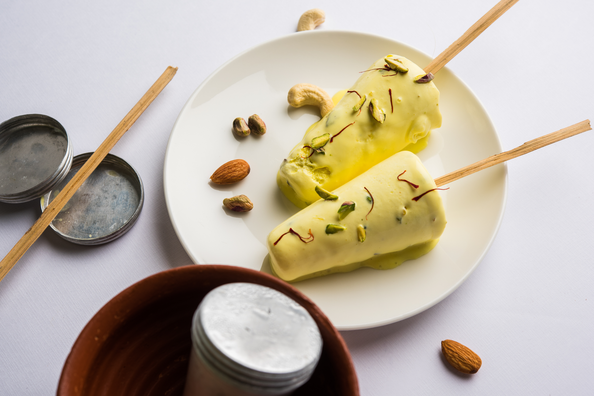 Overhead flat-lay of all ingredients for Floral Indian Cardamom Kulfi with Roasted Almond Topping laid out on a kitchen surface.