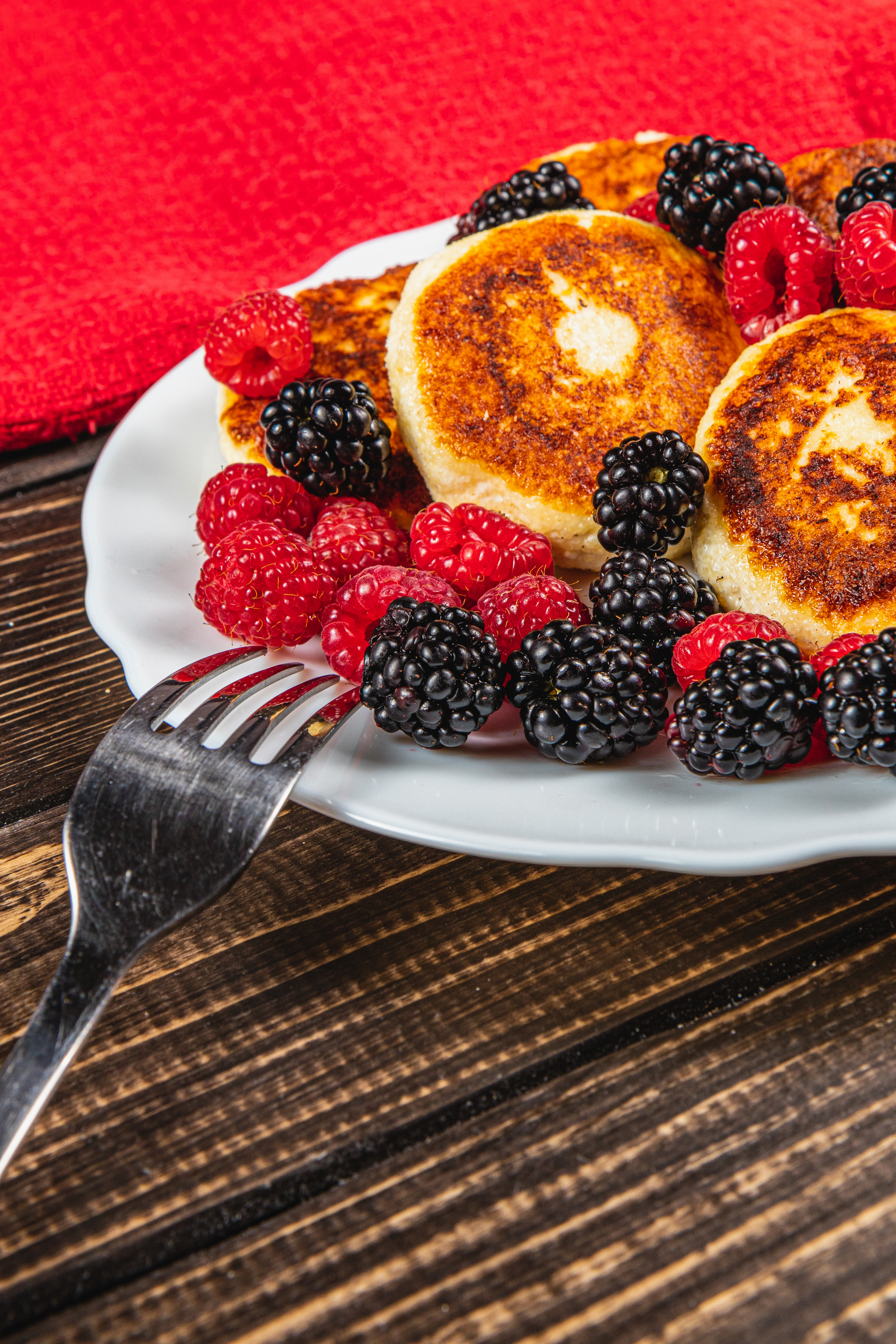 Overhead flat-lay of all ingredients for Fluffy Russian Syrniki with Berries and Honey laid out on a kitchen surface.