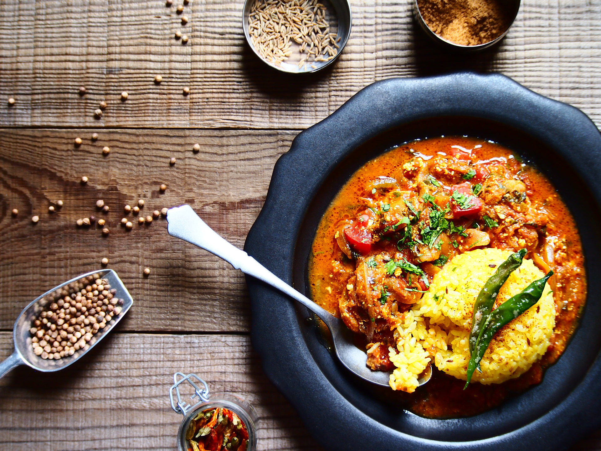 Overhead flat-lay of all ingredients for Fragrant Indian Rogan Josh laid out on a kitchen surface.