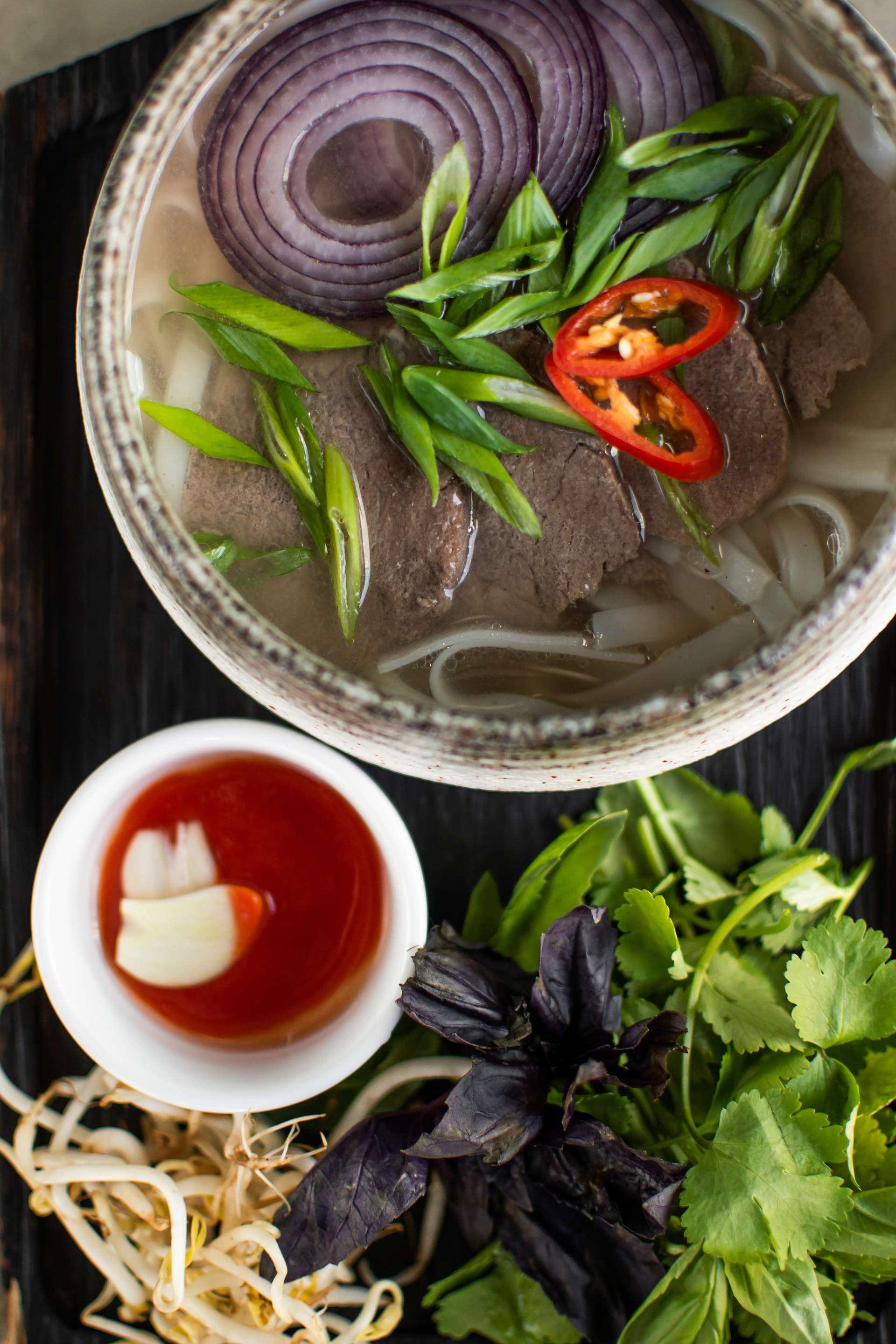 Overhead flat-lay of all ingredients for Fragrant Vietnamese Bun Bo Hue with Spiced Broth laid out on a kitchen surface.