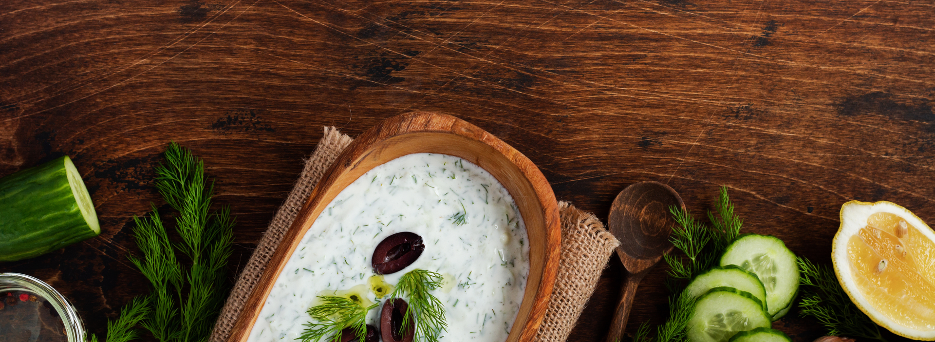 Overhead flat-lay of all ingredients for Fresh Greek Tzatziki laid out on a kitchen surface.