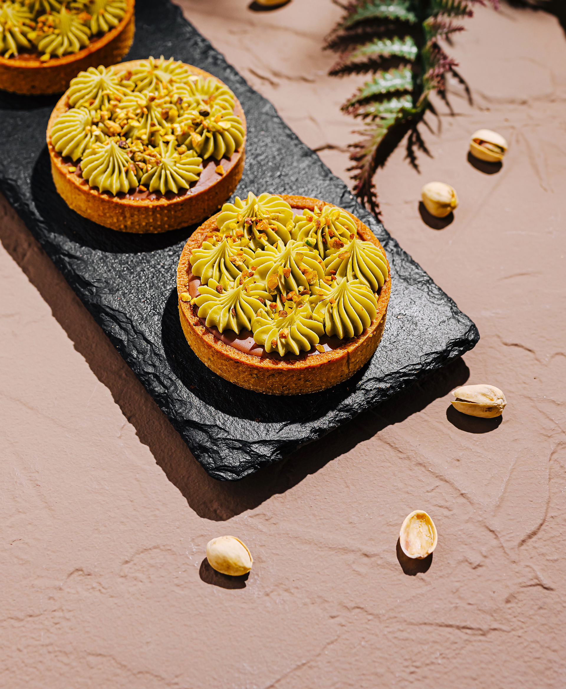Overhead flat-lay of all ingredients for Fruity Moroccan Date and Orange Blossom Tarts with Pistachio Dust laid out on a kitchen surface.