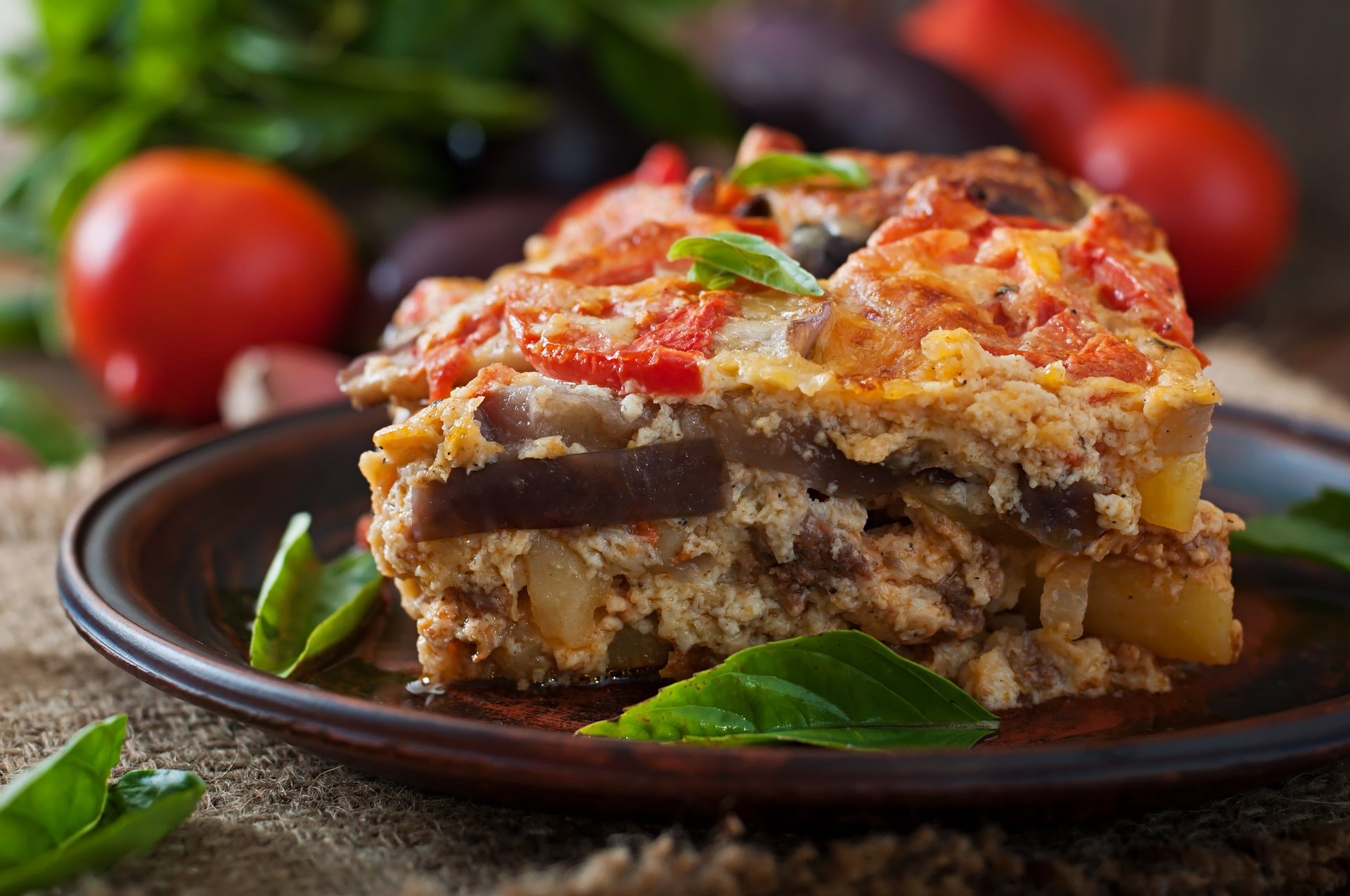 Overhead flat-lay of all ingredients for Greek Eggplant Moussaka laid out on a kitchen surface.
