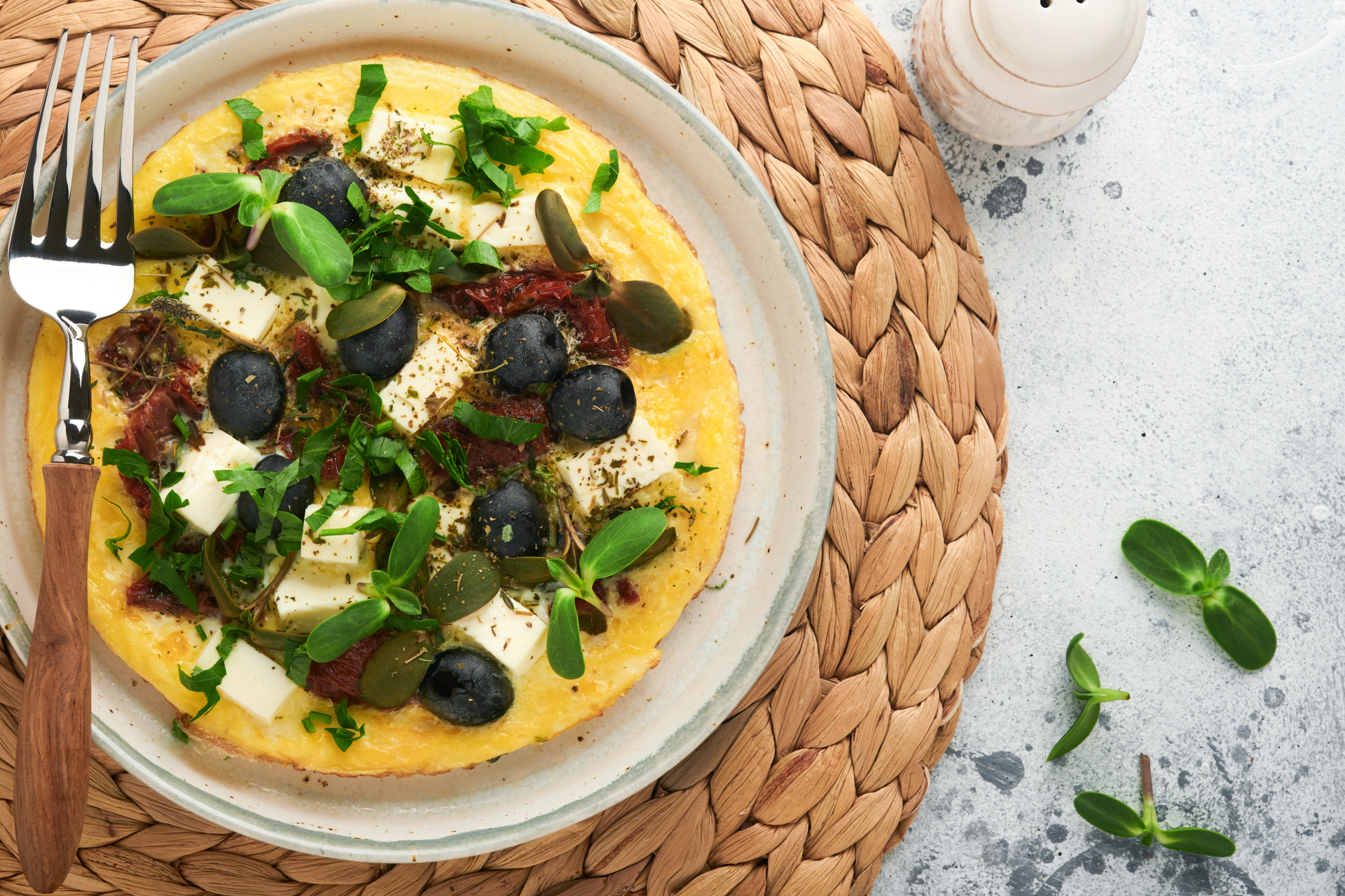 Overhead flat-lay of all ingredients for Greek Kalamata Olive and Feta Frittata with Oregano Infusion laid out on a kitchen surface.
