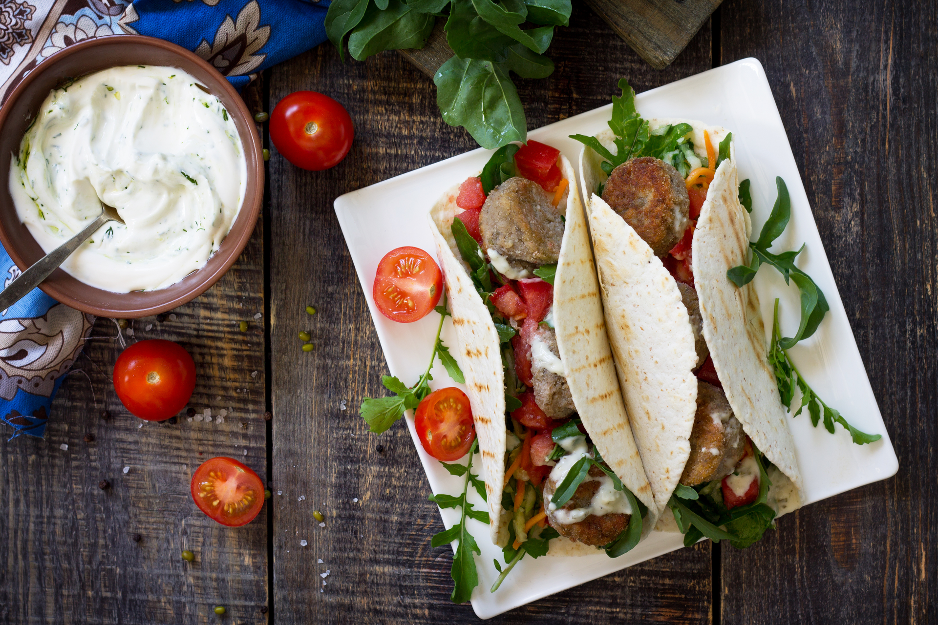Overhead flat-lay of all ingredients for Greek Souvlaki with Tzatziki and Pita laid out on a kitchen surface.