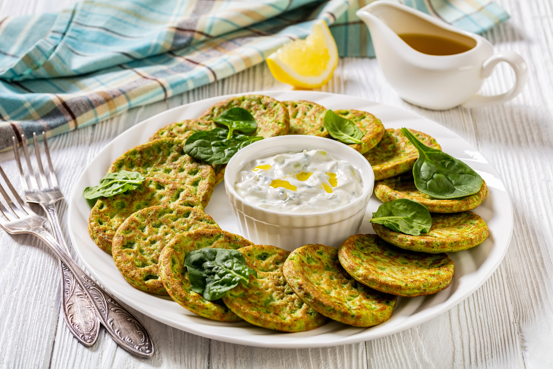 Overhead flat-lay of all ingredients for Greek Zucchini Fritters with Lemon Tzatziki Sauce laid out on a kitchen surface.