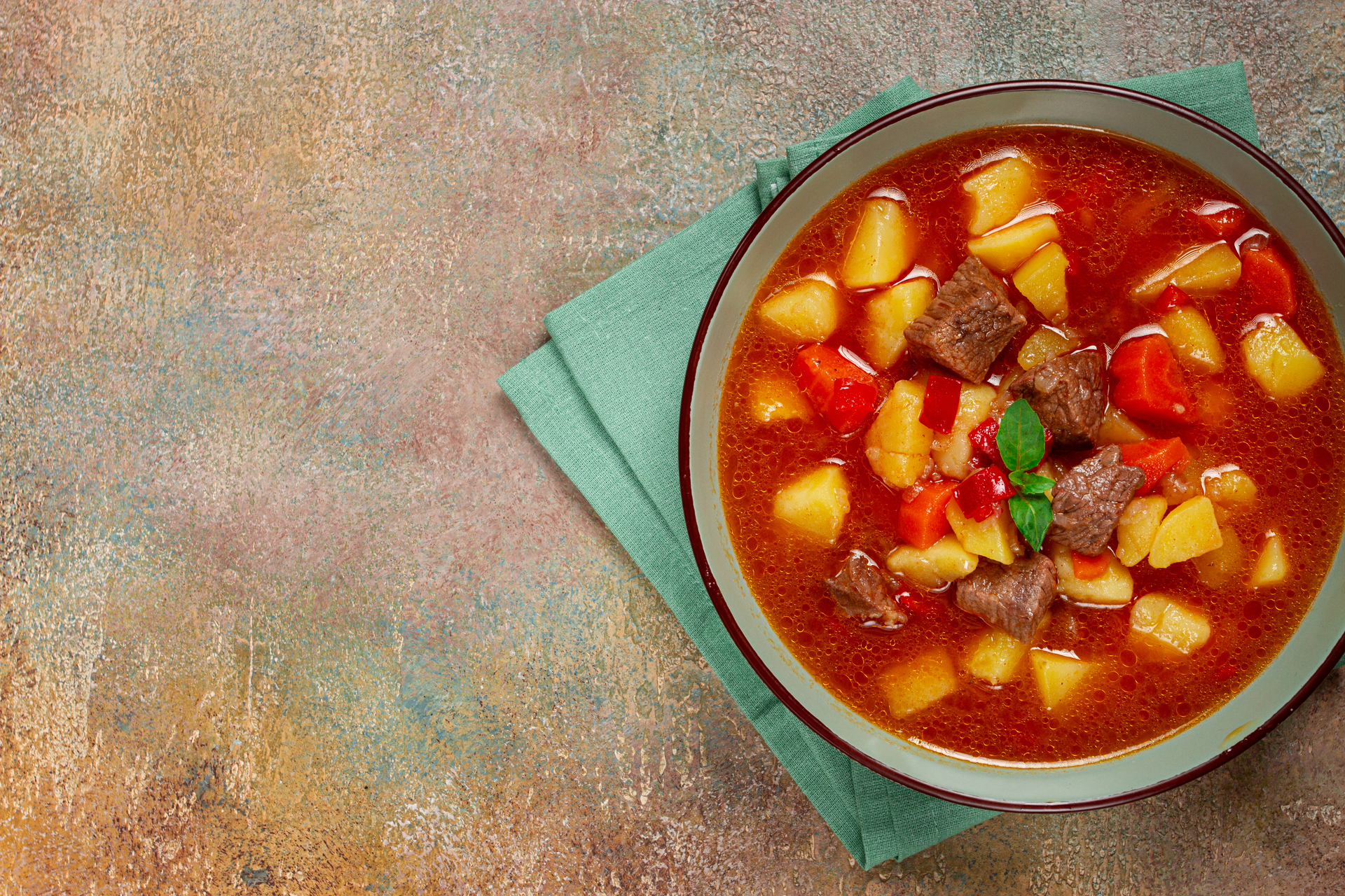 Overhead flat-lay of all ingredients for Hearty Goulash Soup with Beef and Paprika Swirl laid out on a kitchen surface.