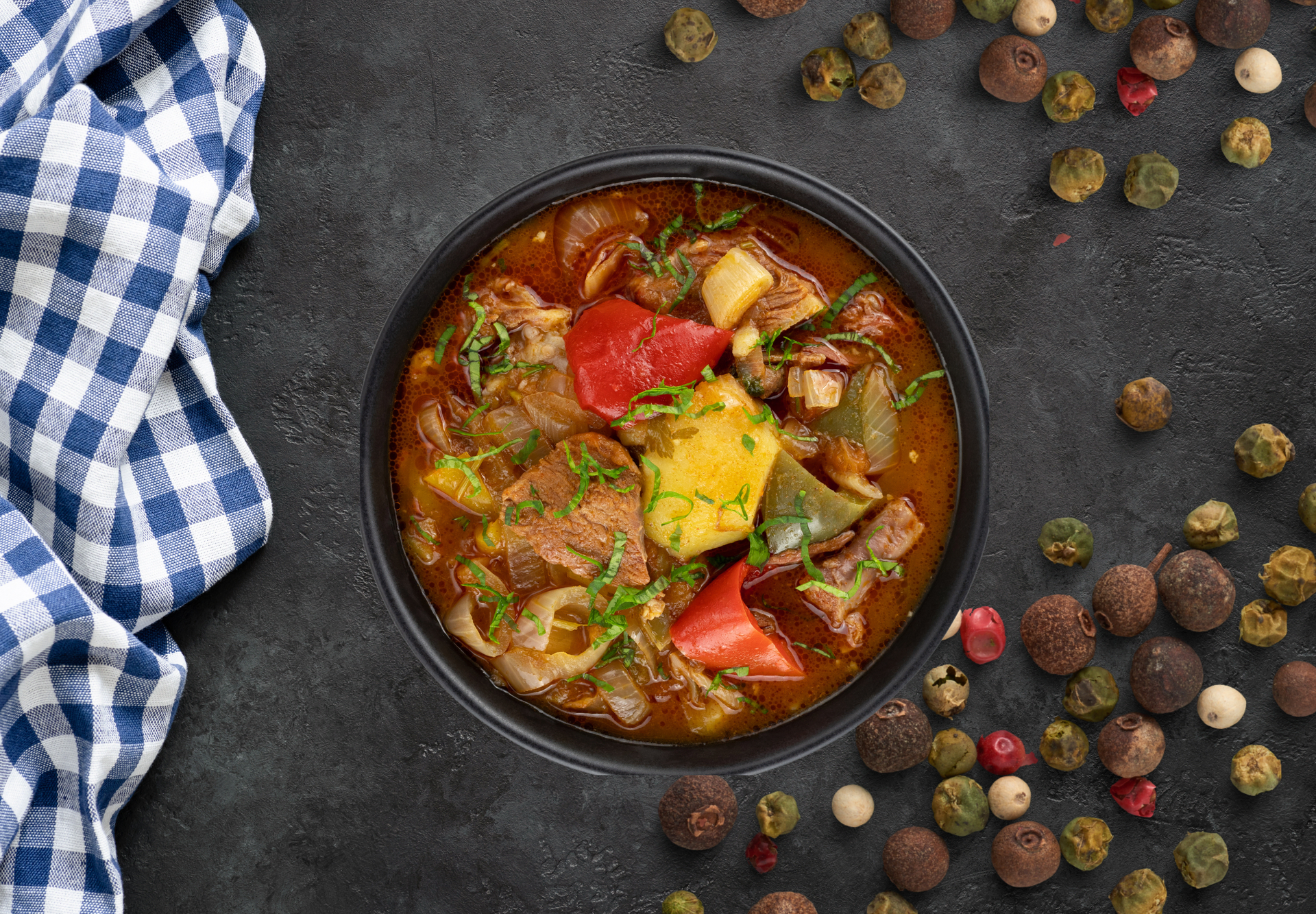 Overhead flat-lay of all ingredients for Hearty Hungarian Gulyás Soup with Beef and Paprika laid out on a kitchen surface.
