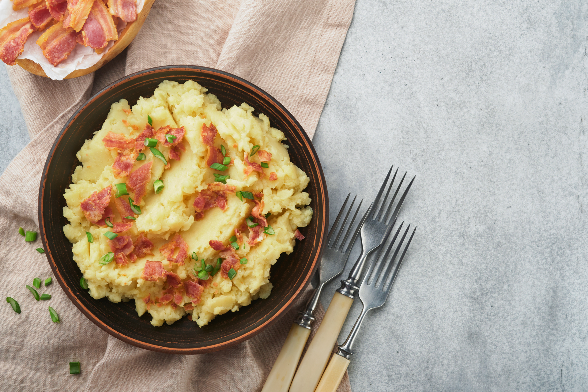 Overhead flat-lay of all ingredients for Hearty Irish Colcannon with Bacon and Green Onions laid out on a kitchen surface.