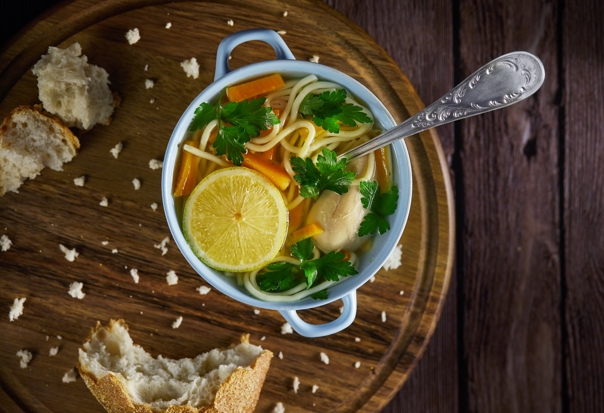 Overhead flat-lay of all ingredients for Greek lemon chicken soup with orzo and fresh herbs laid out on a kitchen surface.