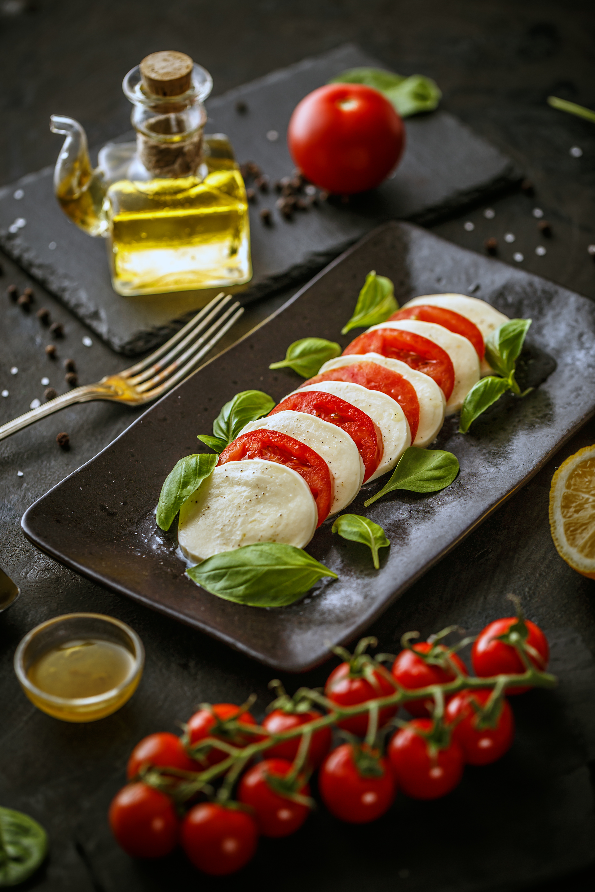 Overhead flat-lay of all ingredients for Herbaceous Italian Caprese Panzanella with Basil Oil Drizzle laid out on a kitchen surface.