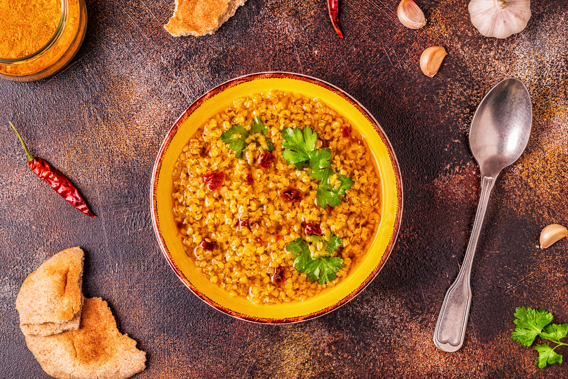 Overhead flat-lay of all ingredients for Hyderabadi Haleem with Wheat and Spices laid out on a kitchen surface.