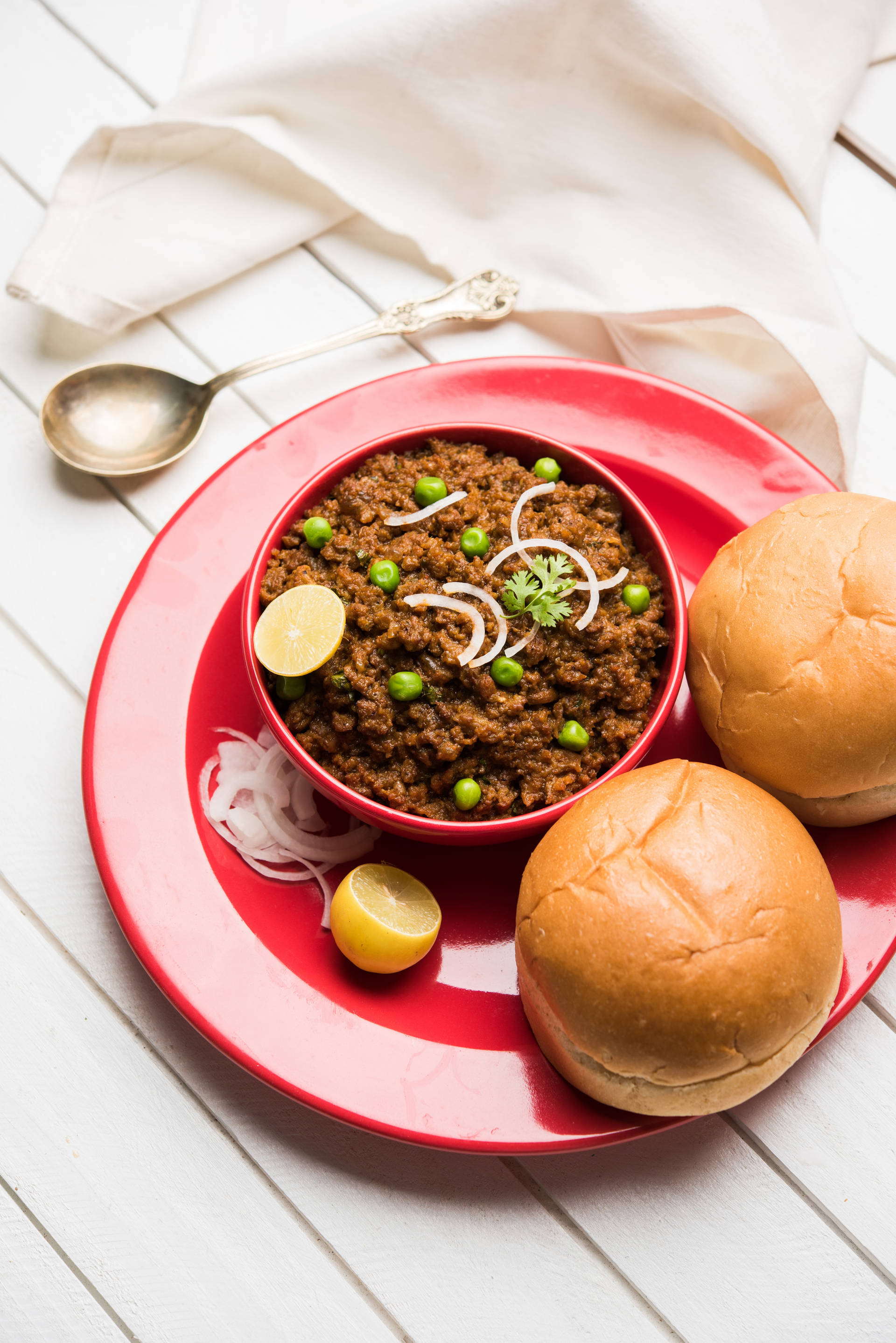 Overhead flat-lay of all ingredients for Indian Keema Pav with Spiced Minced Meat laid out on a kitchen surface.