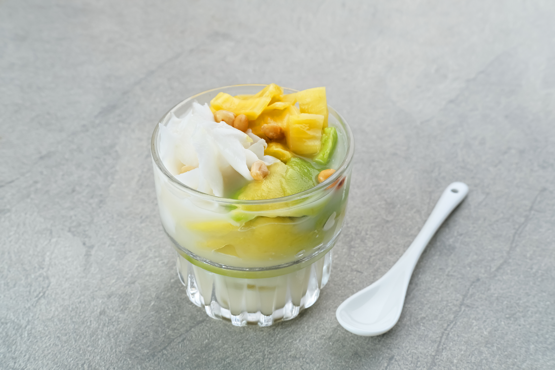 Overhead flat-lay of all ingredients for Indonesian Es Teler with Avocado and Young Coconut laid out on a kitchen surface.