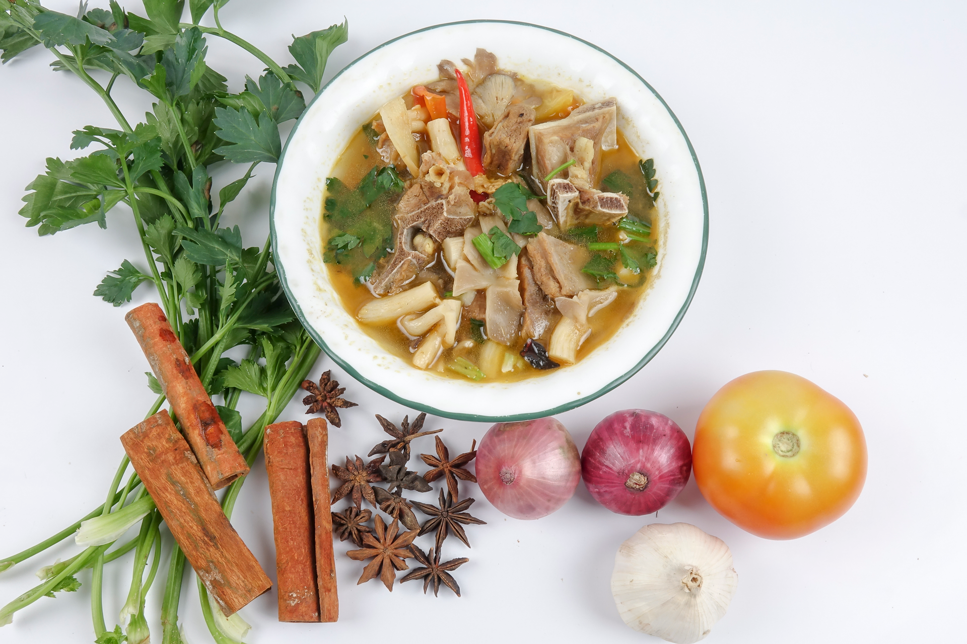 Overhead flat-lay of all ingredients for Indonesian Oxtail Soup with Ginger and Star Anise Broth laid out on a kitchen surface.