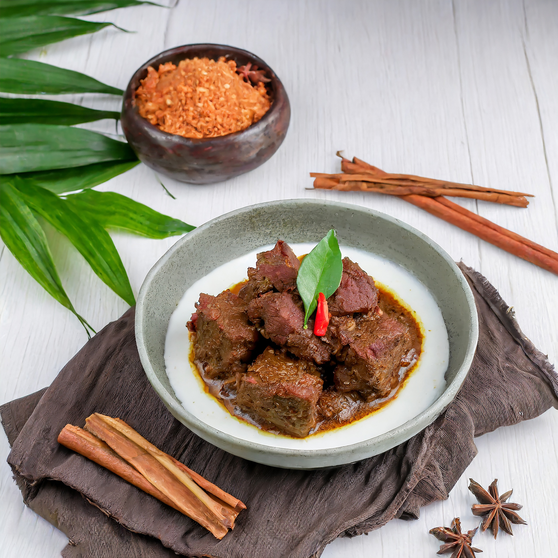 Overhead flat-lay of all ingredients for Indonesian Rendang Daging with Coconut Milk laid out on a kitchen surface.