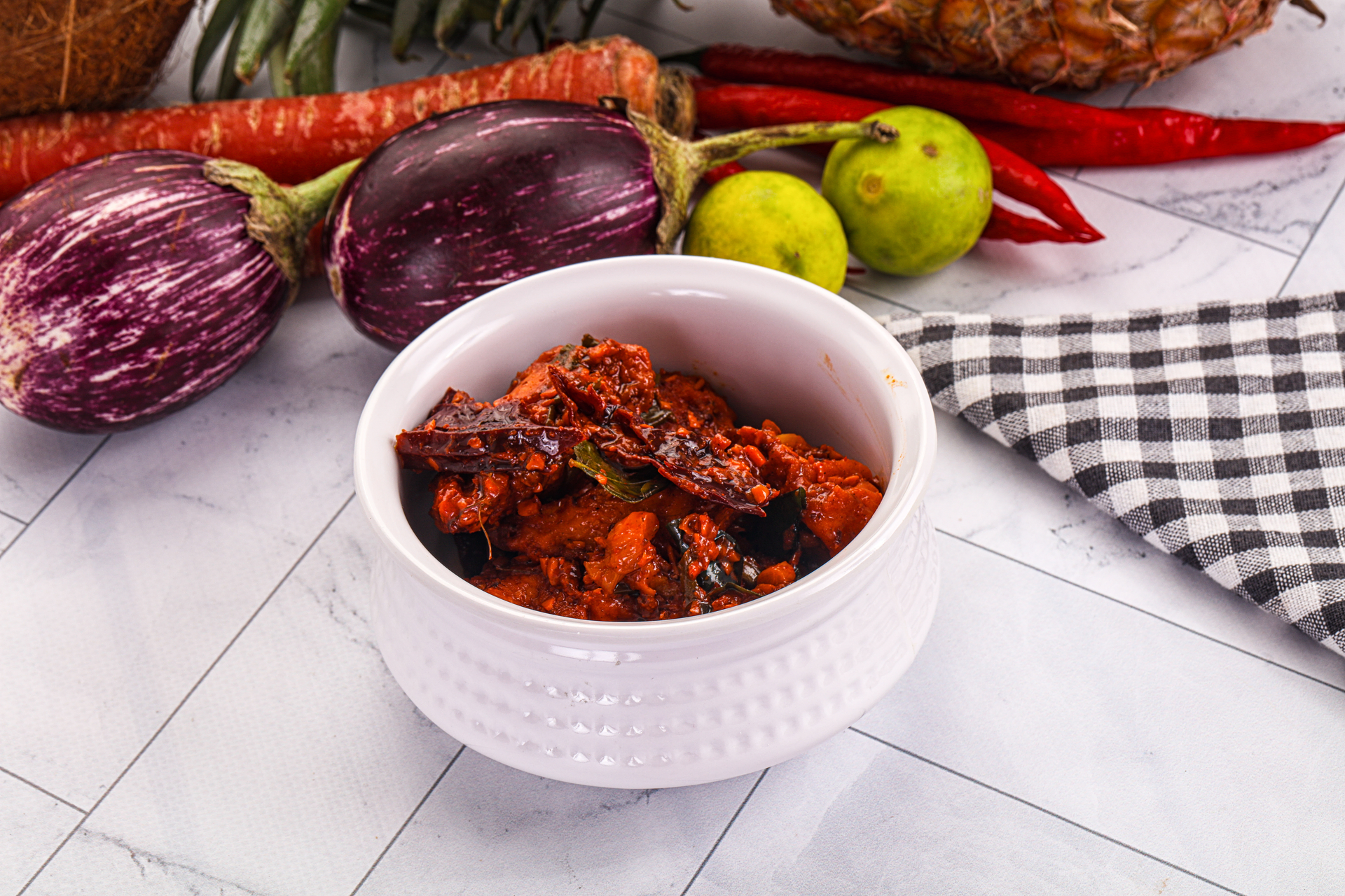 Overhead flat-lay of all ingredients for Indonesian Sambal Belacan with Charred Eggplant and Lime laid out on a kitchen surface.