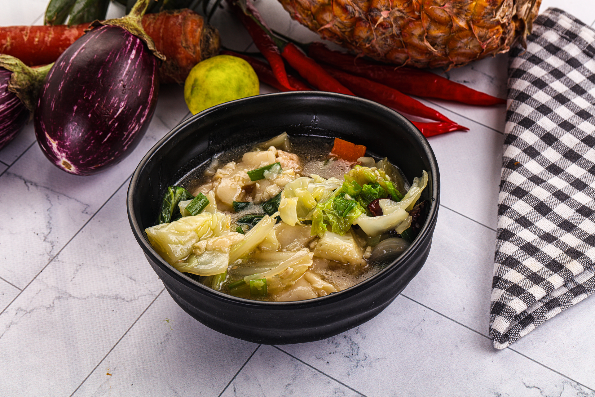 Overhead flat-lay of all ingredients for Indonesian Soto Ayam with Lime and Sambal laid out on a kitchen surface.