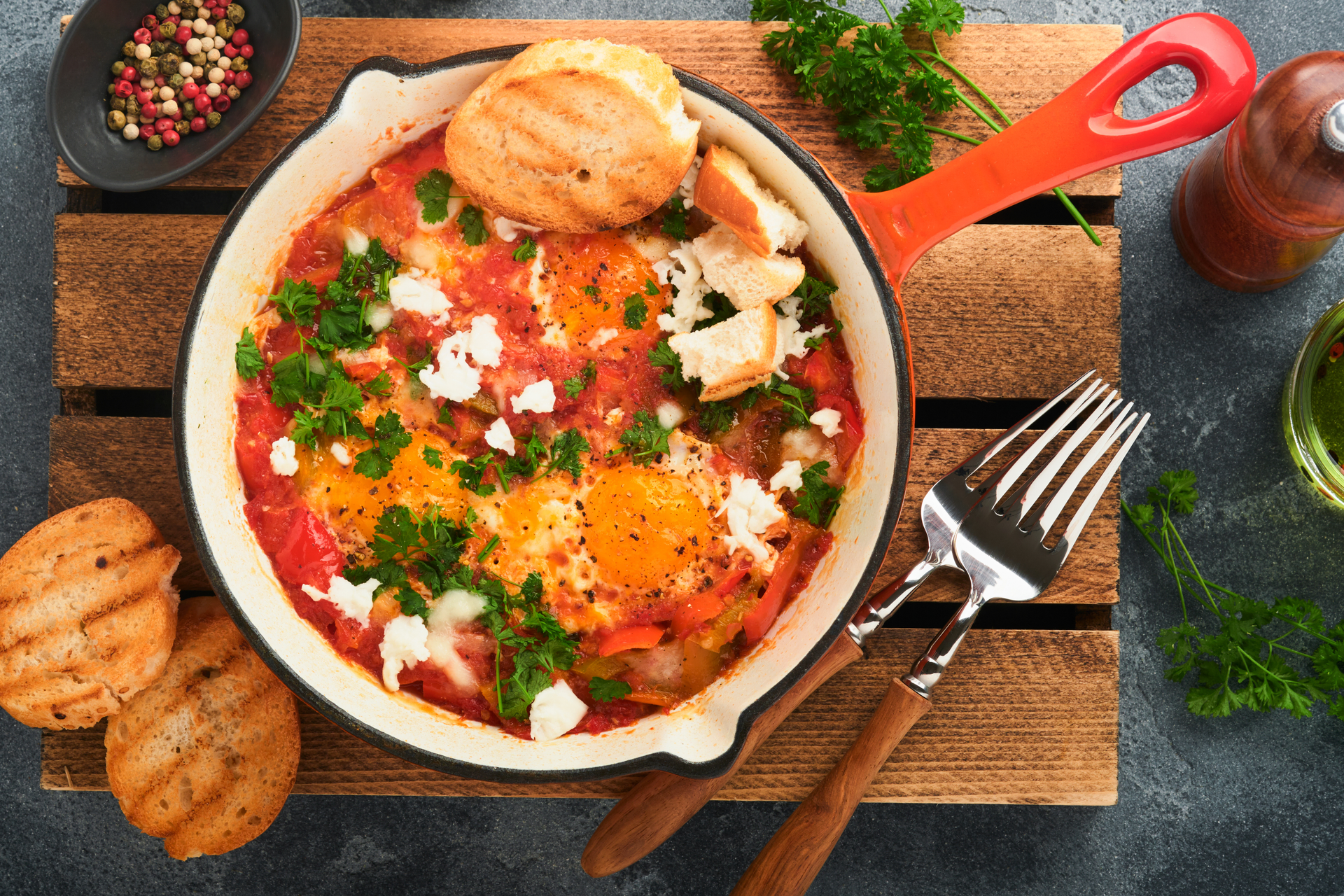 Overhead flat-lay of all ingredients for Israeli Shakshuka with Poached Eggs and Spicy Tomato Sauce laid out on a kitchen surface.